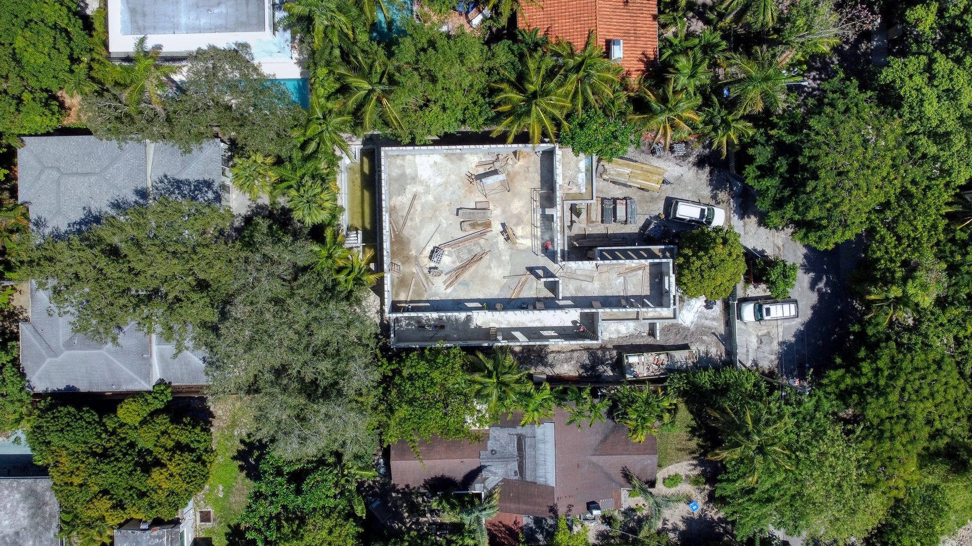 Aerial view of a house surrounded by trees; the roof appears damaged.