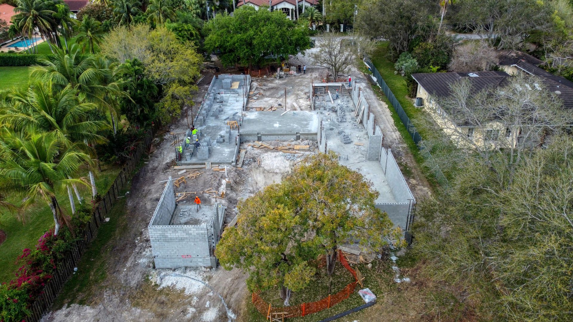 Aerial view of a building under construction. Concrete walls are partially built with debris scattered around.