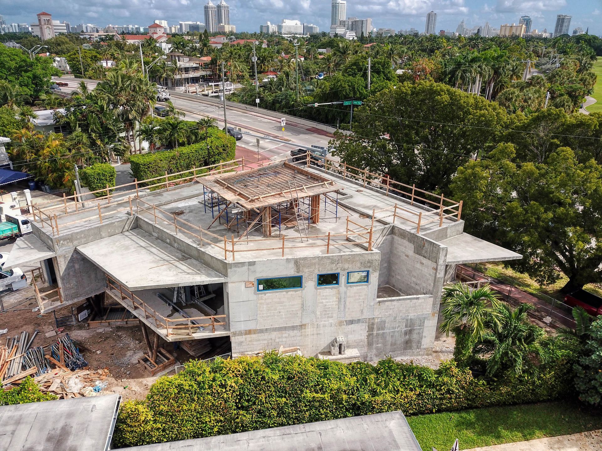 Building under construction with concrete walls, flat roof, and a cityscape in the background.