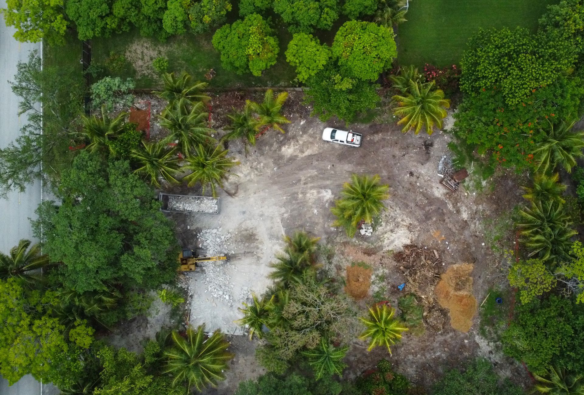 Overhead view of a cleared lot with a vehicle and equipment surrounded by trees.