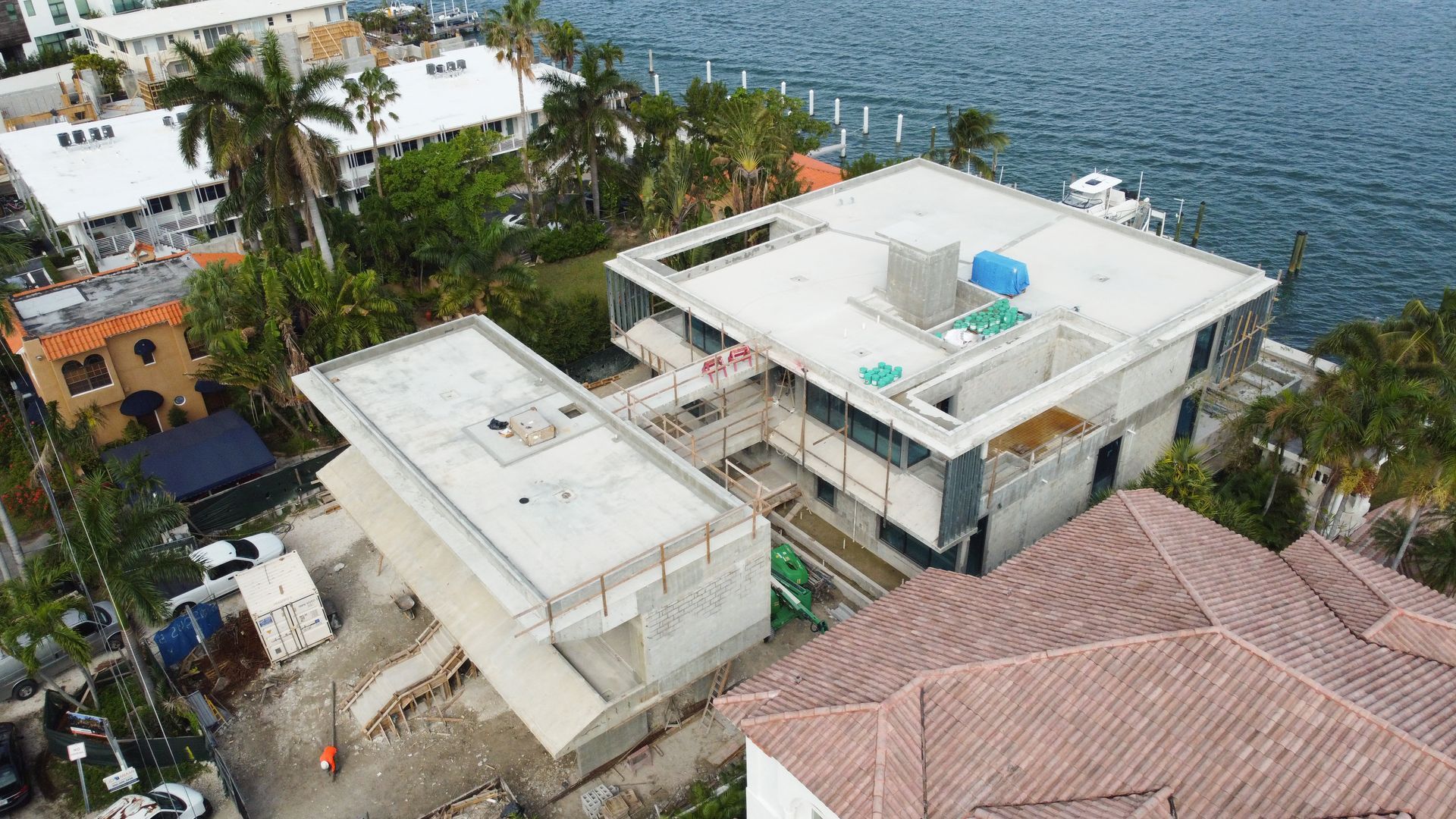 An aerial view of a large house under construction next to a body of water.