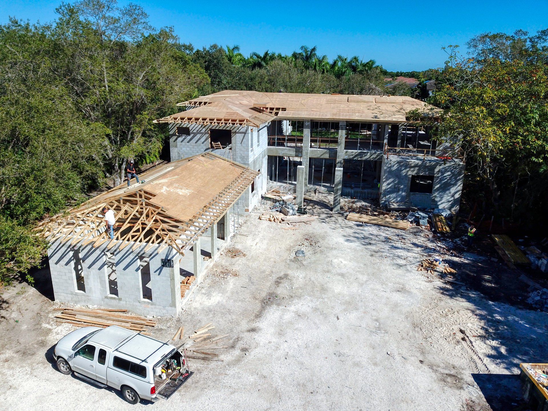 Construction of a large two-story house, with framing and unfinished walls. A van is parked nearby.