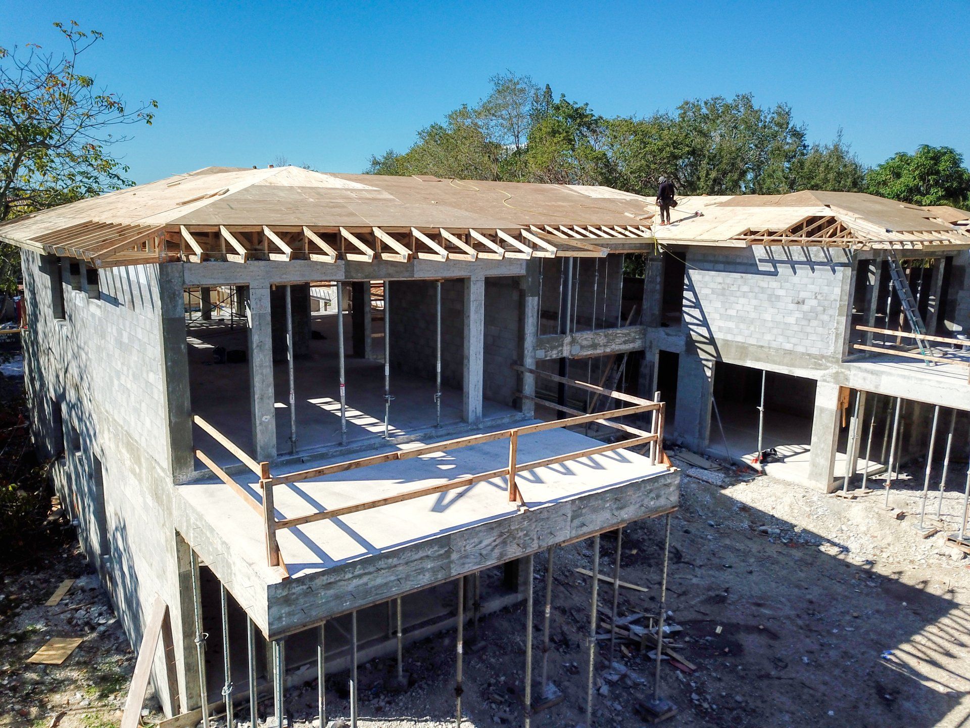 Building under construction with concrete walls, wood framing, and a partially built roof, outdoors.