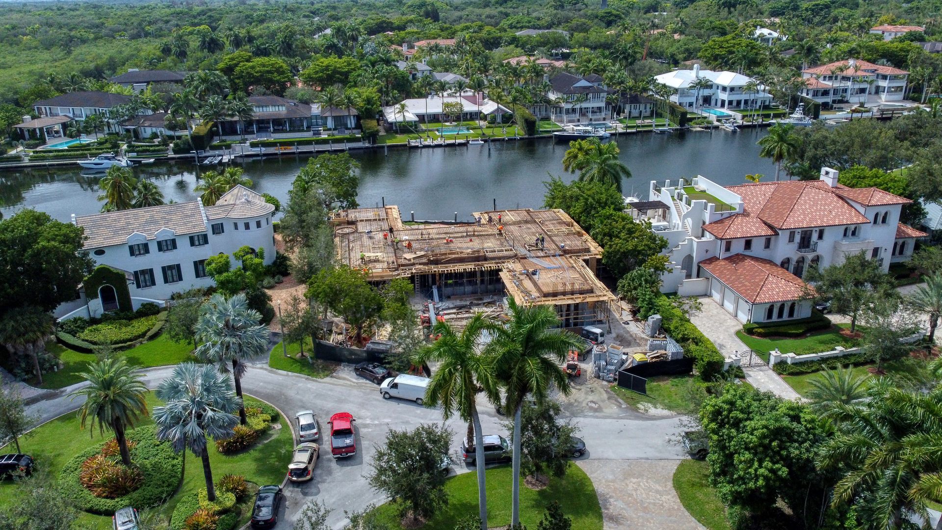 Aerial view of a home with a destroyed roof, surrounded by other houses and water.