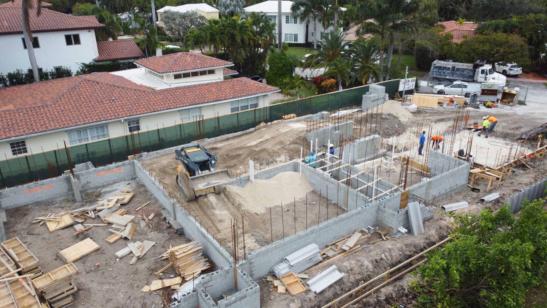 An aerial view of a construction site with a house in the background.