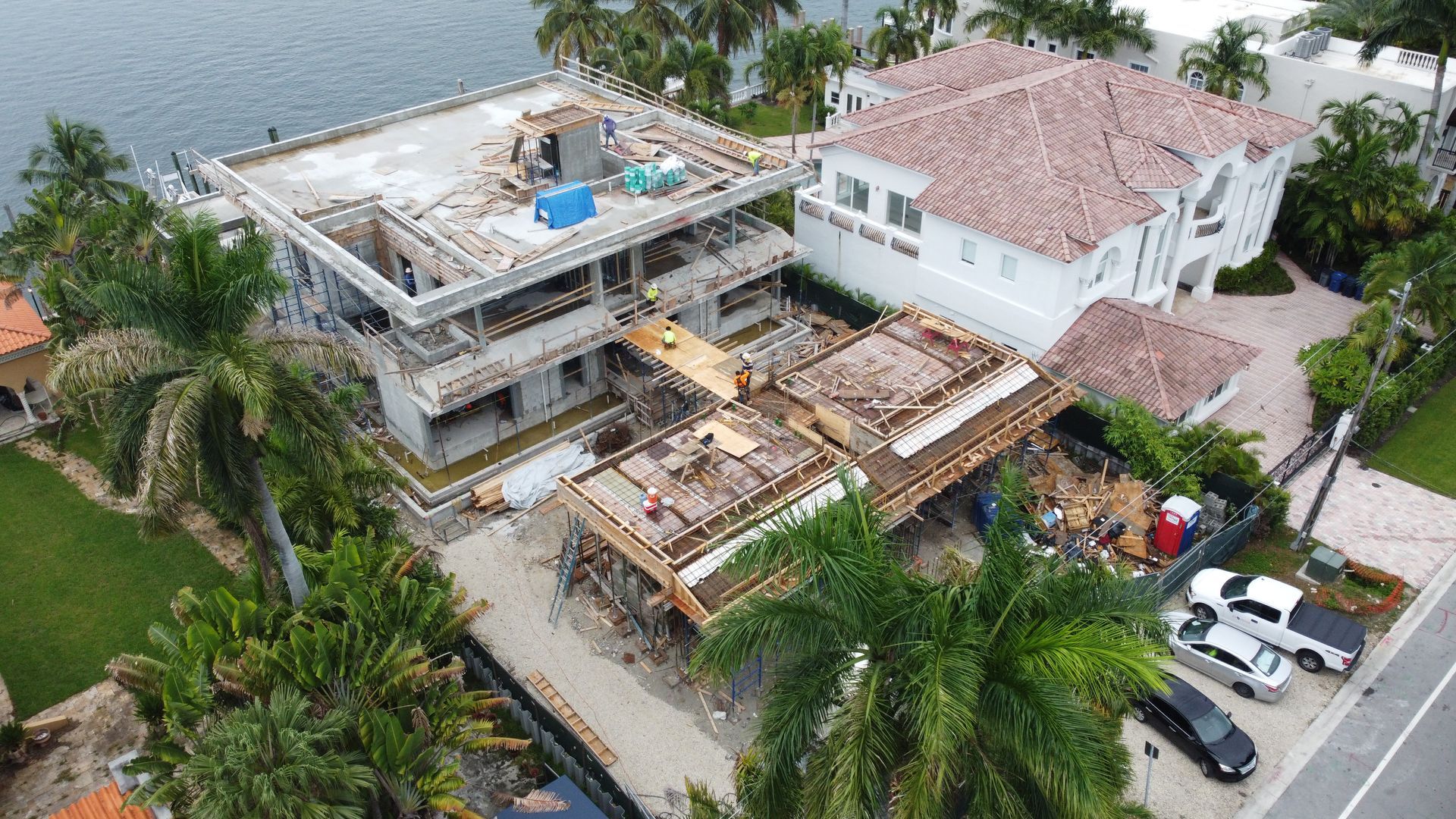 An aerial view of a large house under construction next to a body of water.