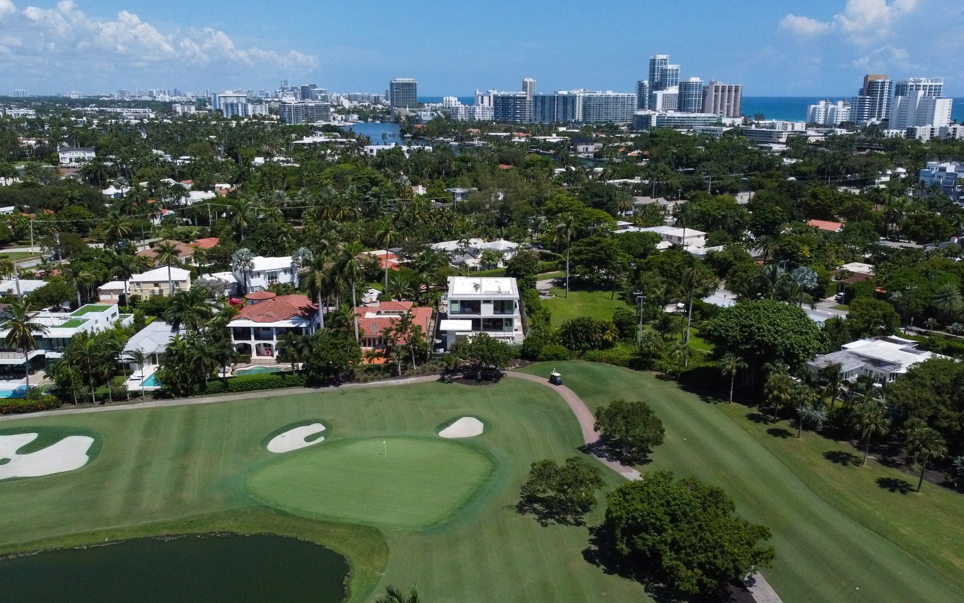 An aerial view of a golf course with a city in the background