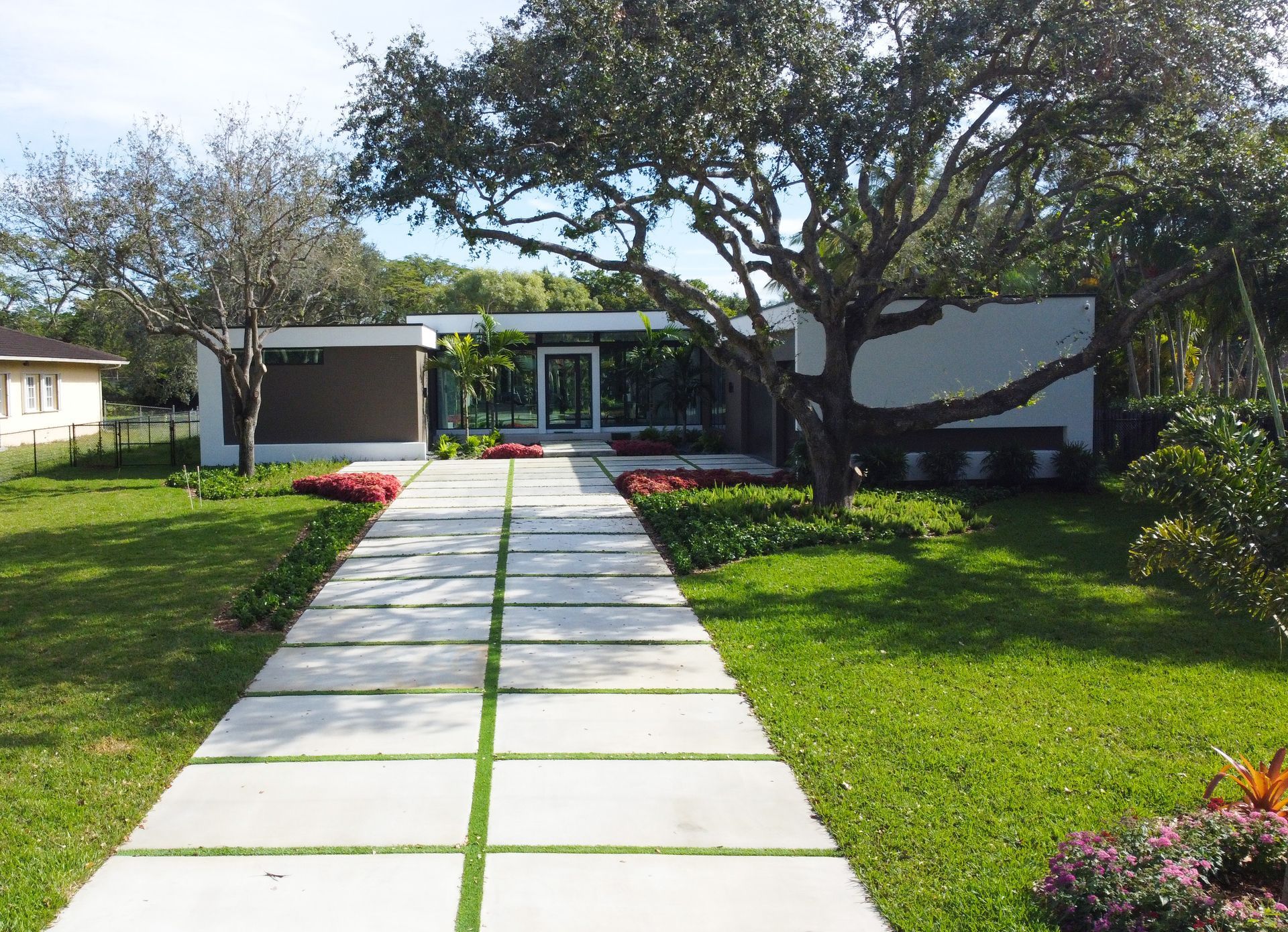 Modern home with a stone path leading to the entrance, flanked by grass and landscaping.