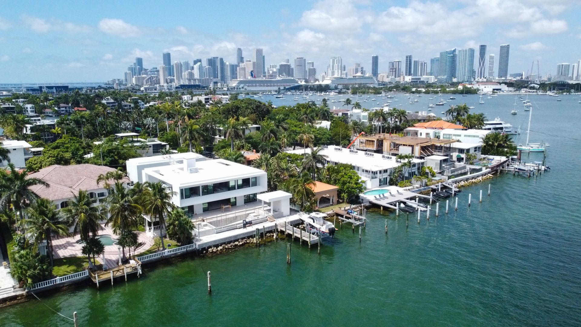 An aerial view of a residential area next to a body of water with a city skyline in the background.