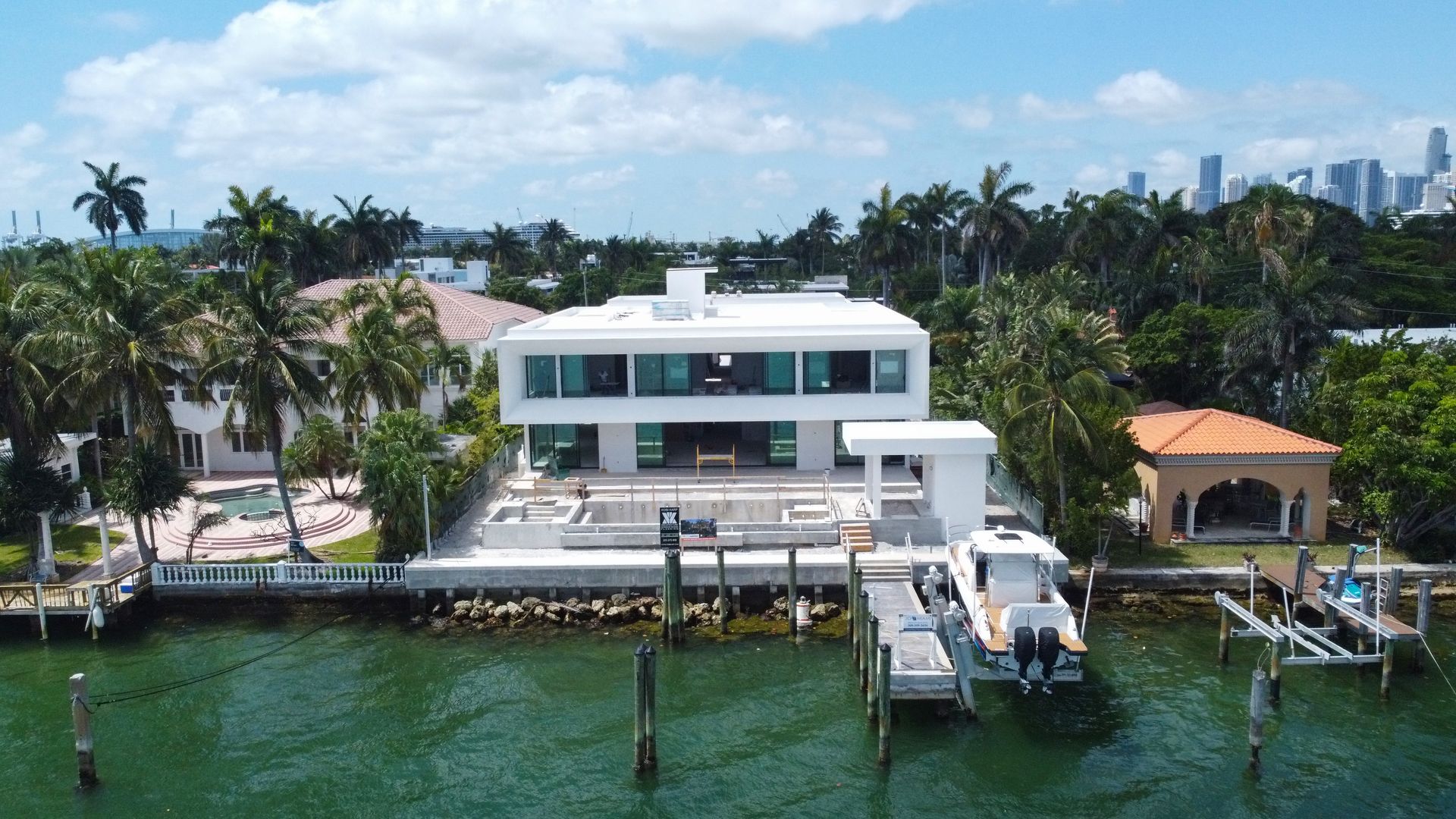 An aerial view of a large white house with a boat docked in front of it