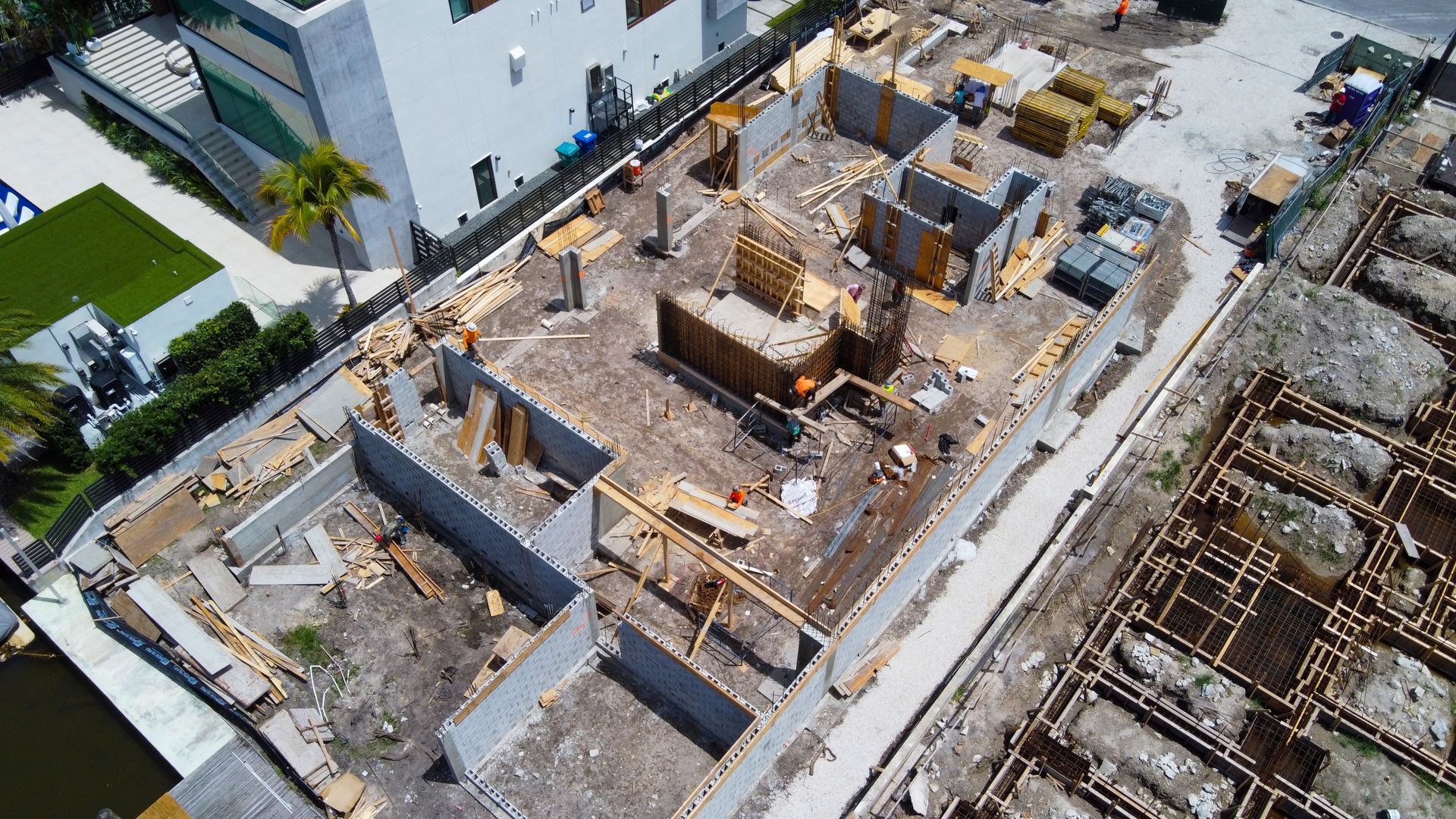 Aerial view of a building under construction, showing concrete foundations and wood framing, in an urban setting.