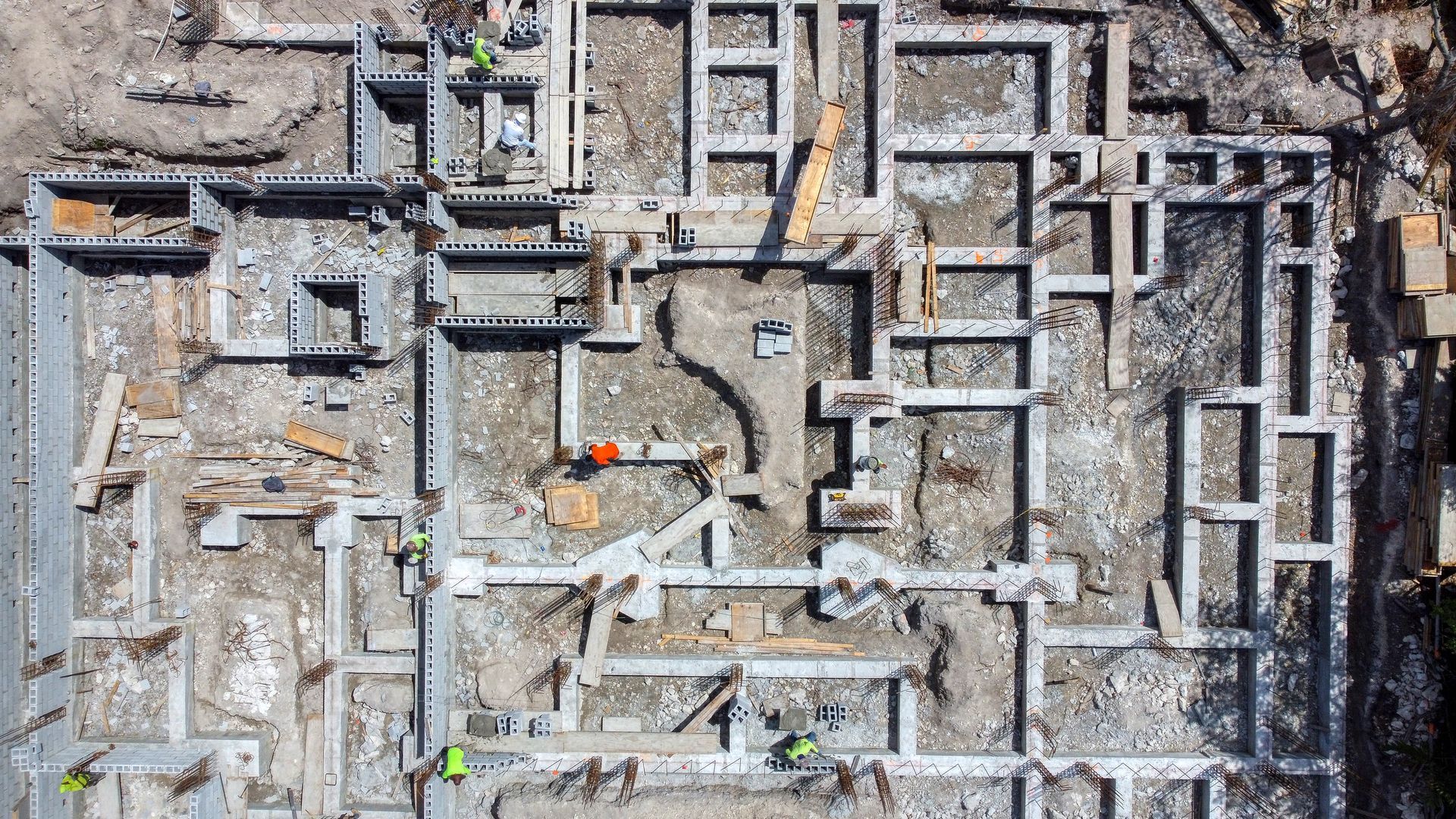 Overhead view of a construction site with concrete foundations and some workers.