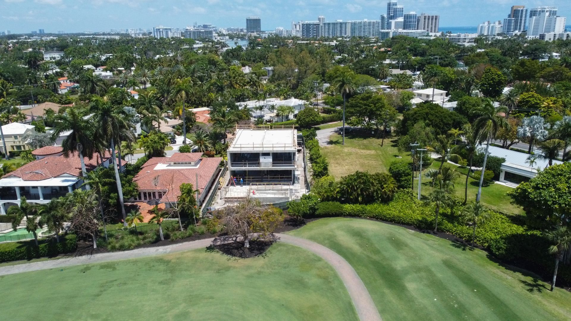 An aerial view of a golf course with a house in the background.