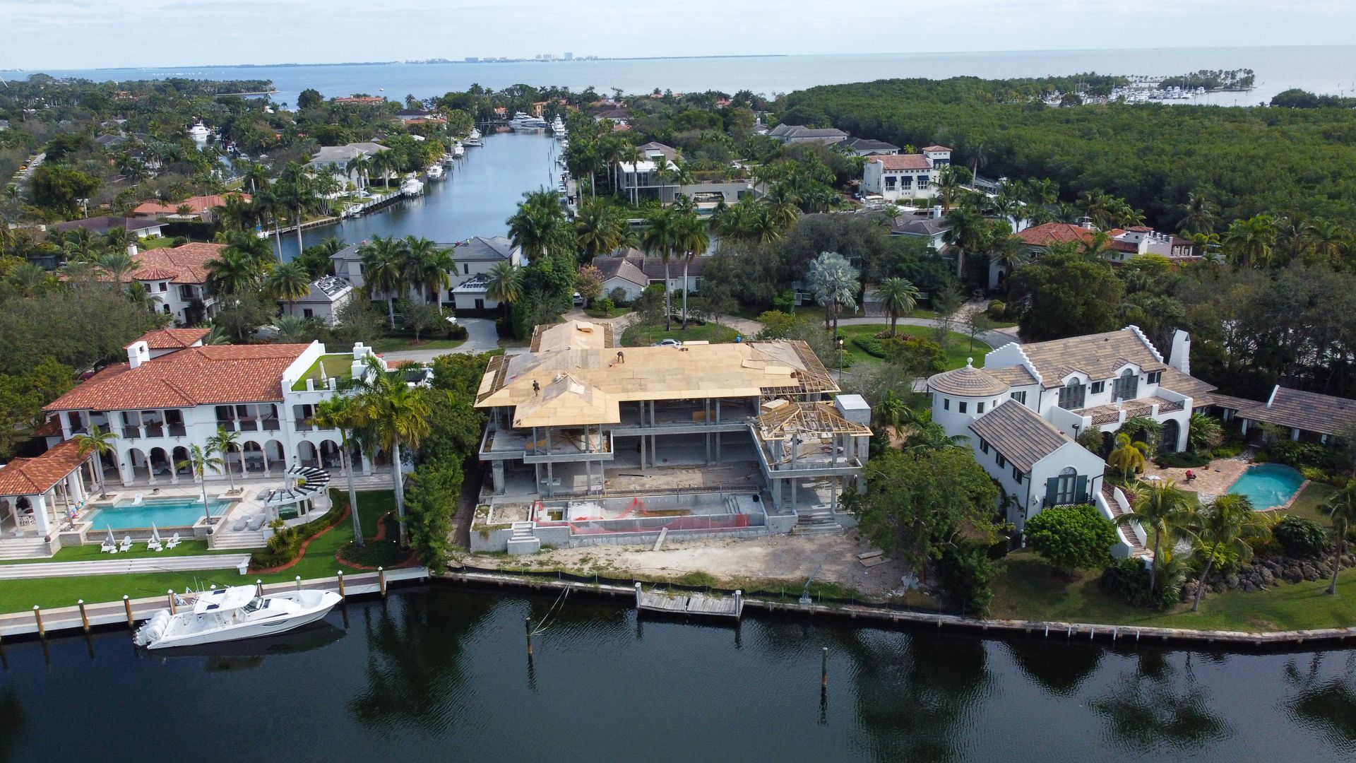 Aerial view of waterfront homes, one under construction, on a canal leading to the ocean.