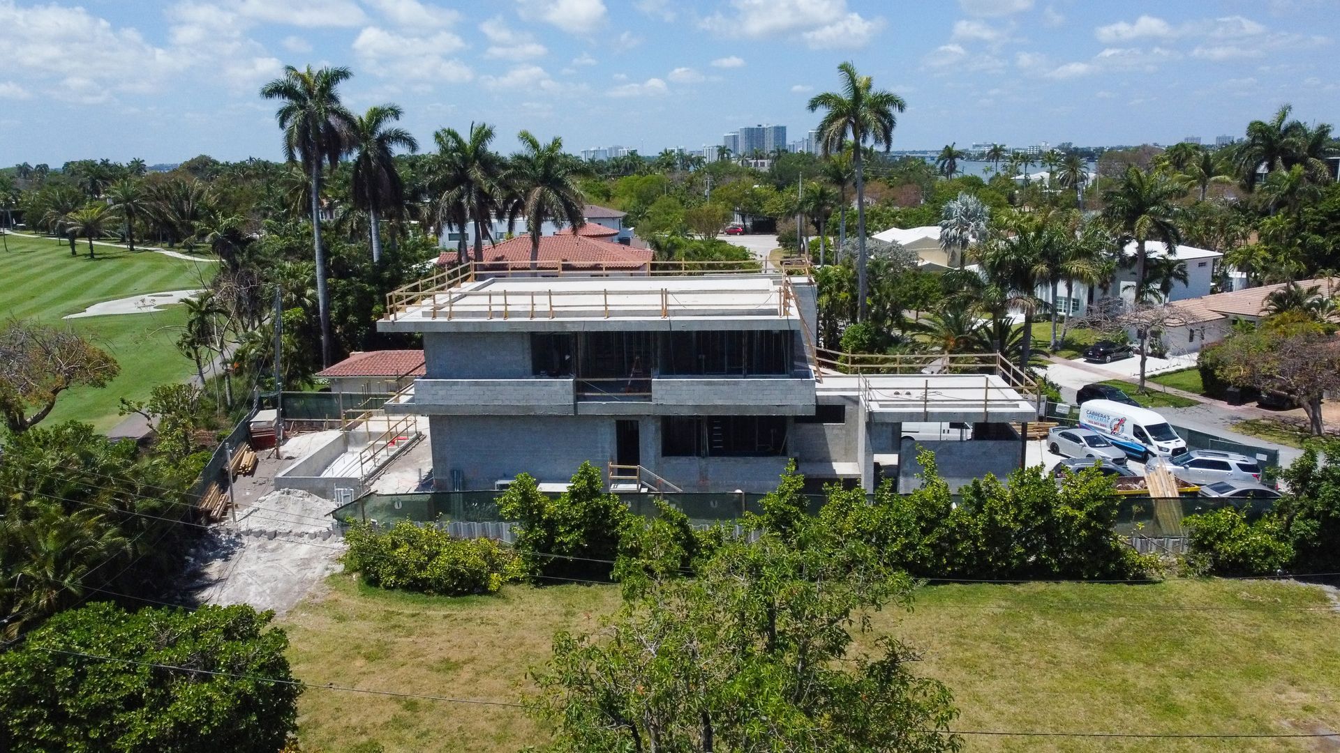 An aerial view of a house under construction with a golf course in the background