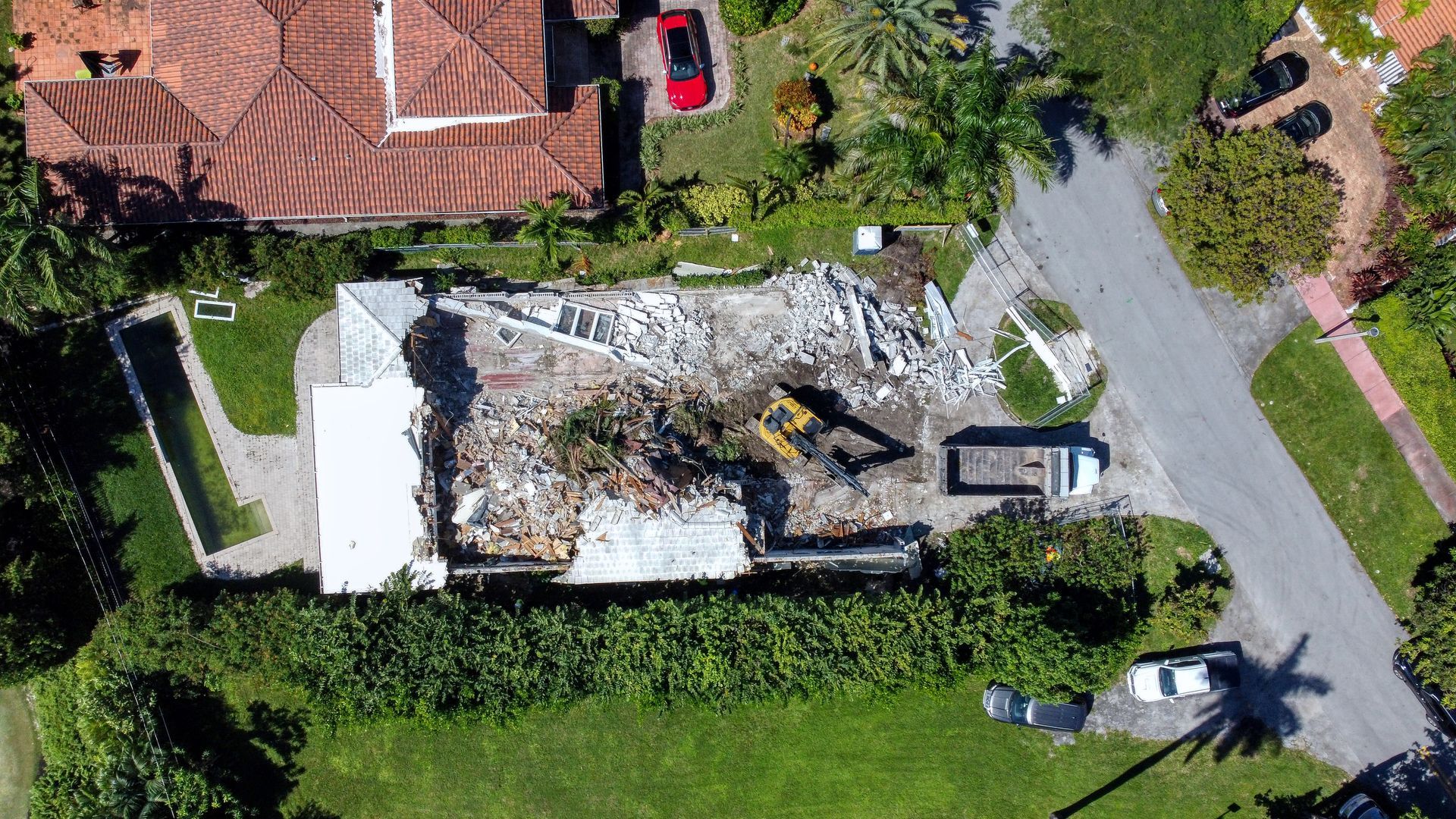 An aerial view of a house being demolished in a residential area.
