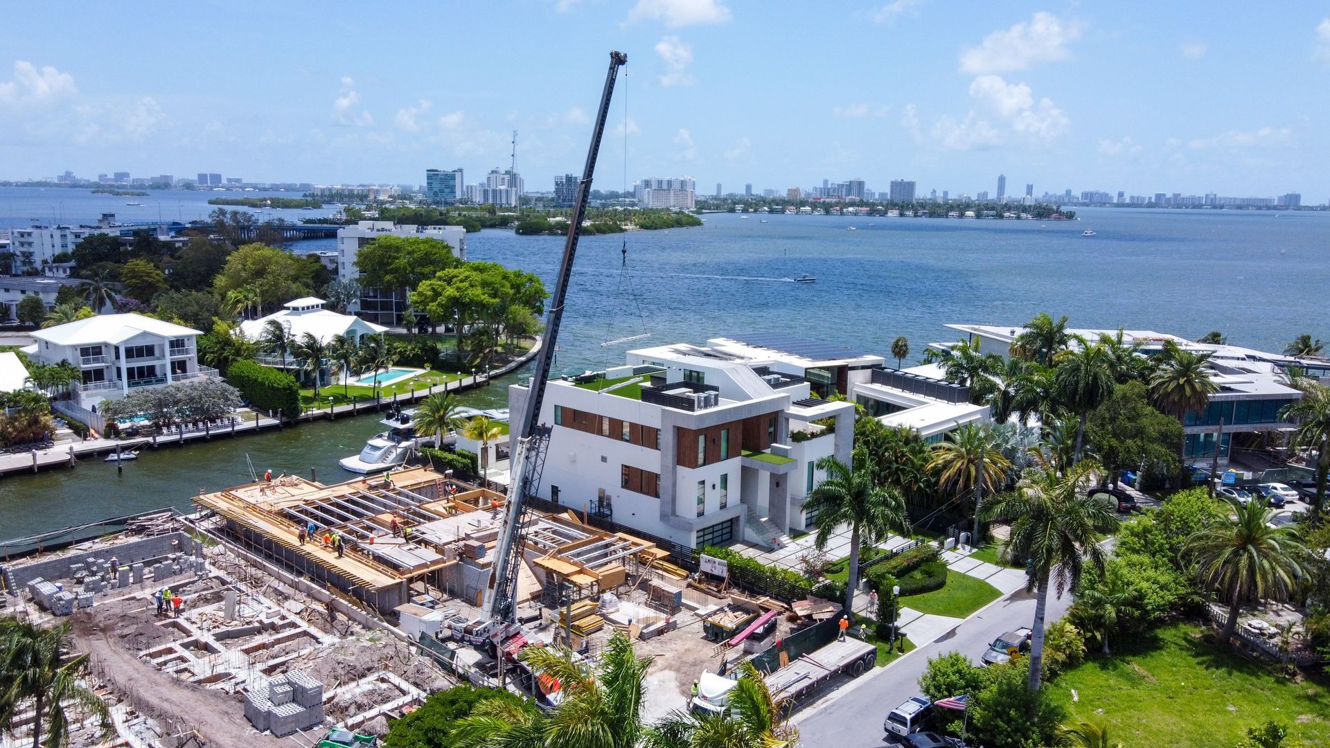 Construction site with crane near waterfront houses.
