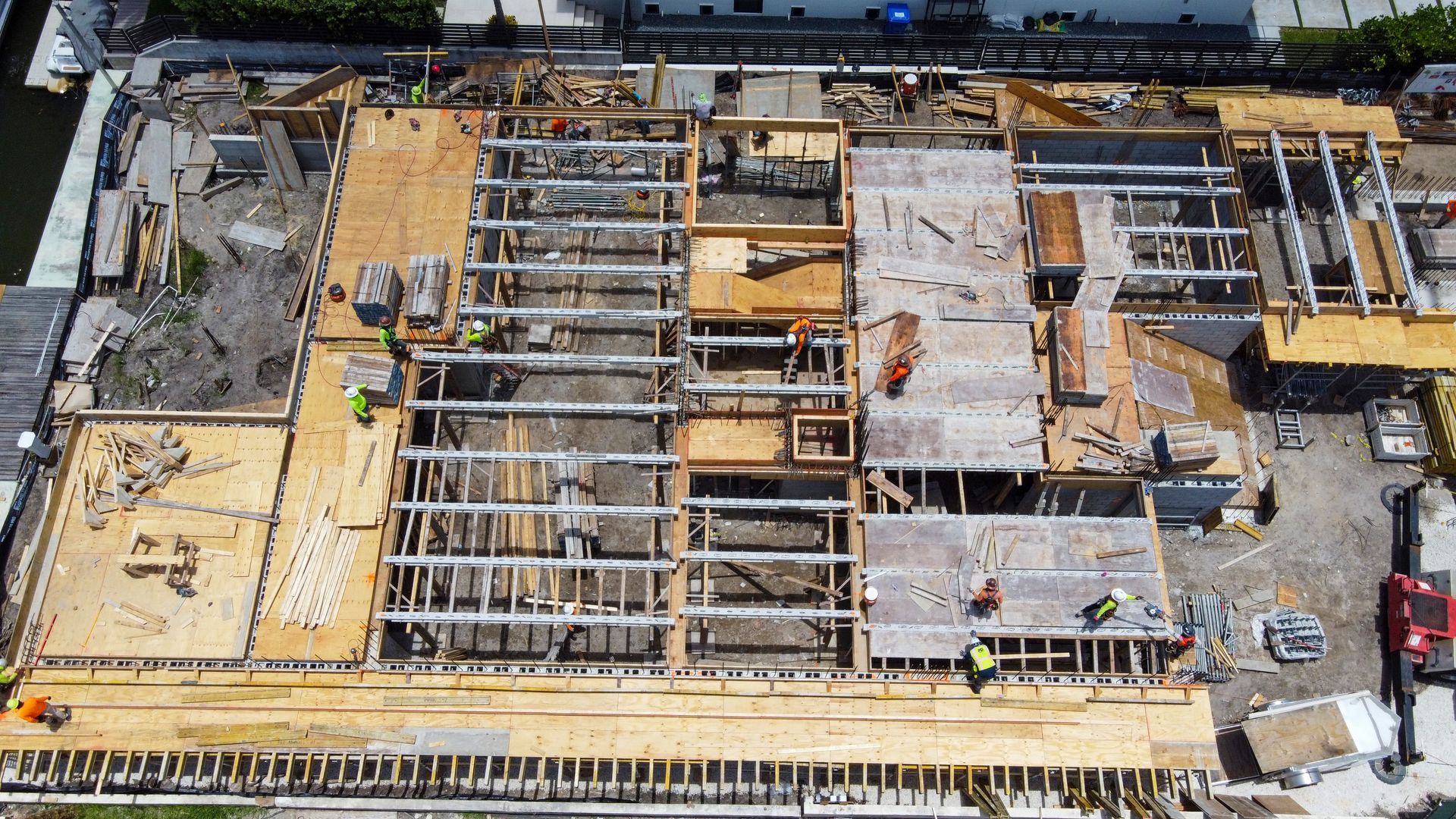 Aerial view of a building under construction, showing wooden framing and workers.