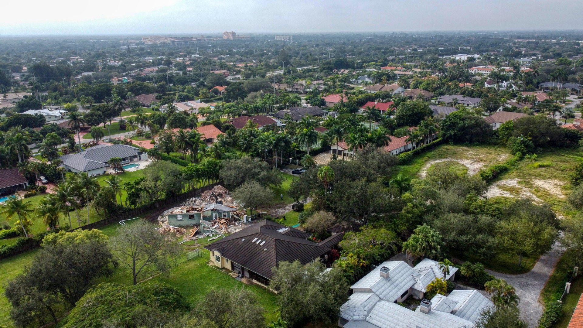 Aerial view of a suburban neighborhood with houses, trees, and green lawns on a sunny day.