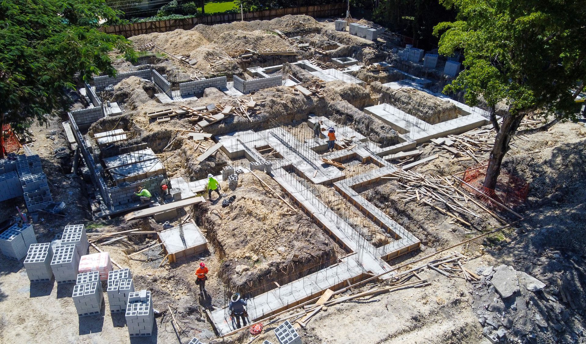 Construction site foundation with workers; concrete blocks and trenches.