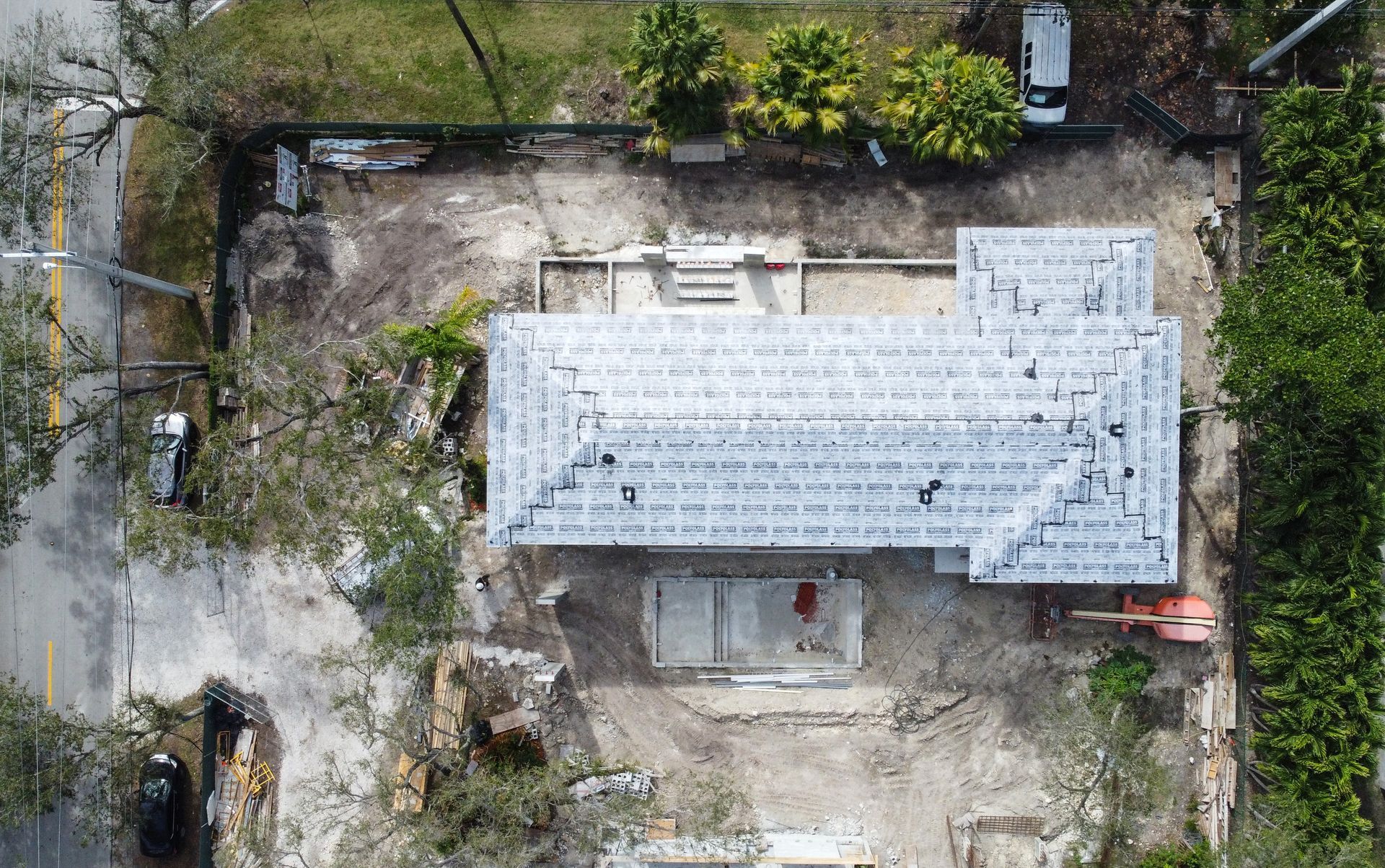 Aerial view of a building under construction, showing a partially completed roof and surrounding yard.