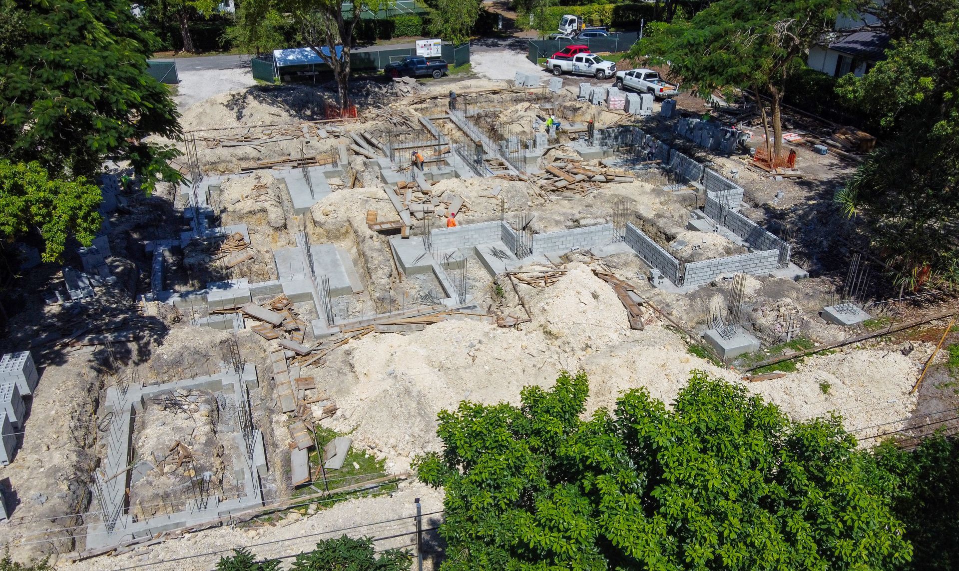 Construction site from above, with foundations, debris, and equipment; sunny day.