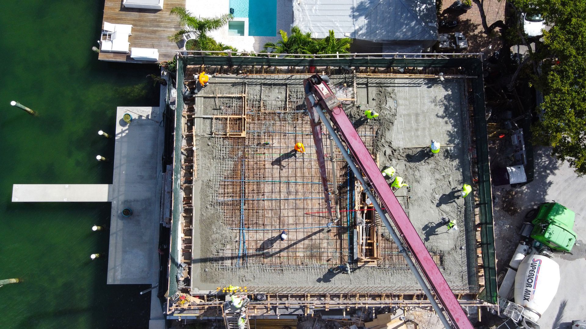 Construction site with workers pouring concrete; aerial view.