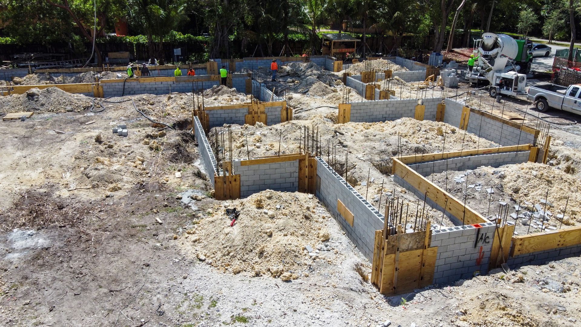 Construction site with concrete foundation walls, wooden forms, and workers.