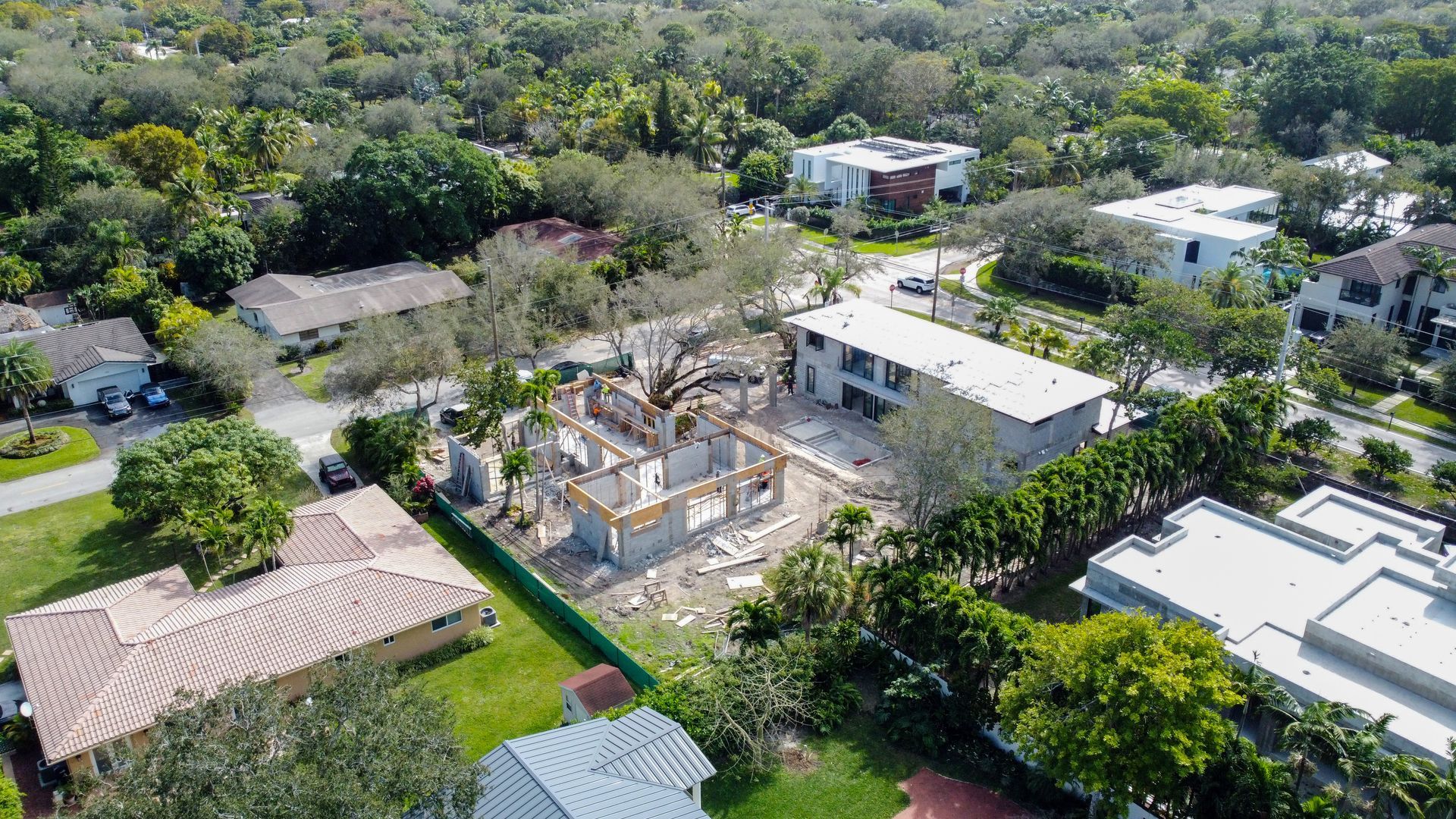 Aerial view of residential construction, surrounded by houses and trees.