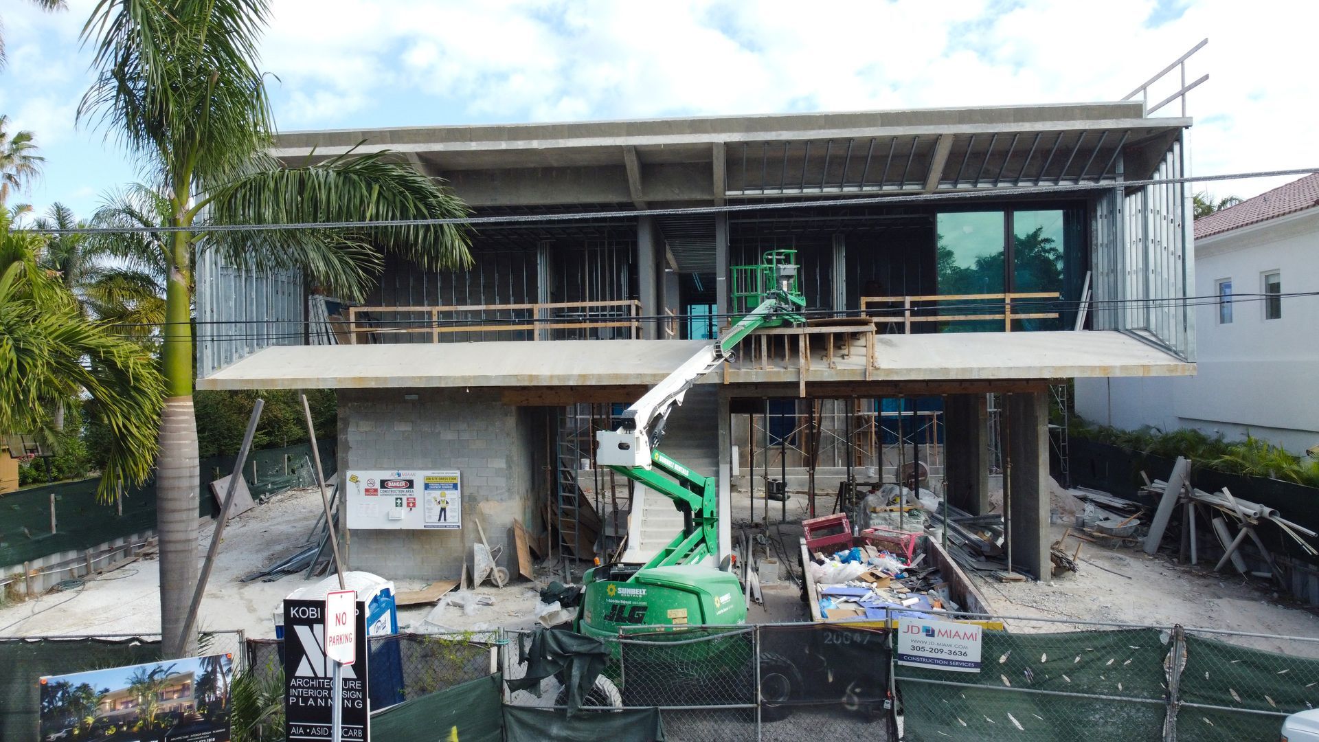 A large house is being built with a green crane in front of it.