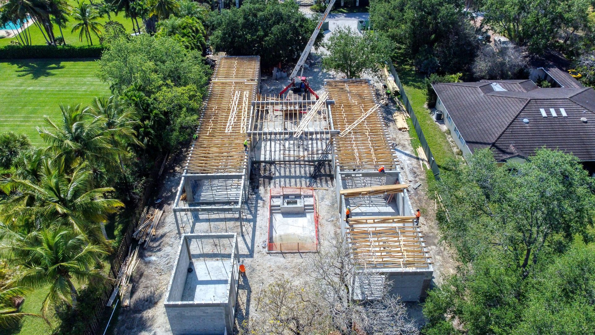 Construction site with partially built rectangular structures, surrounded by trees.