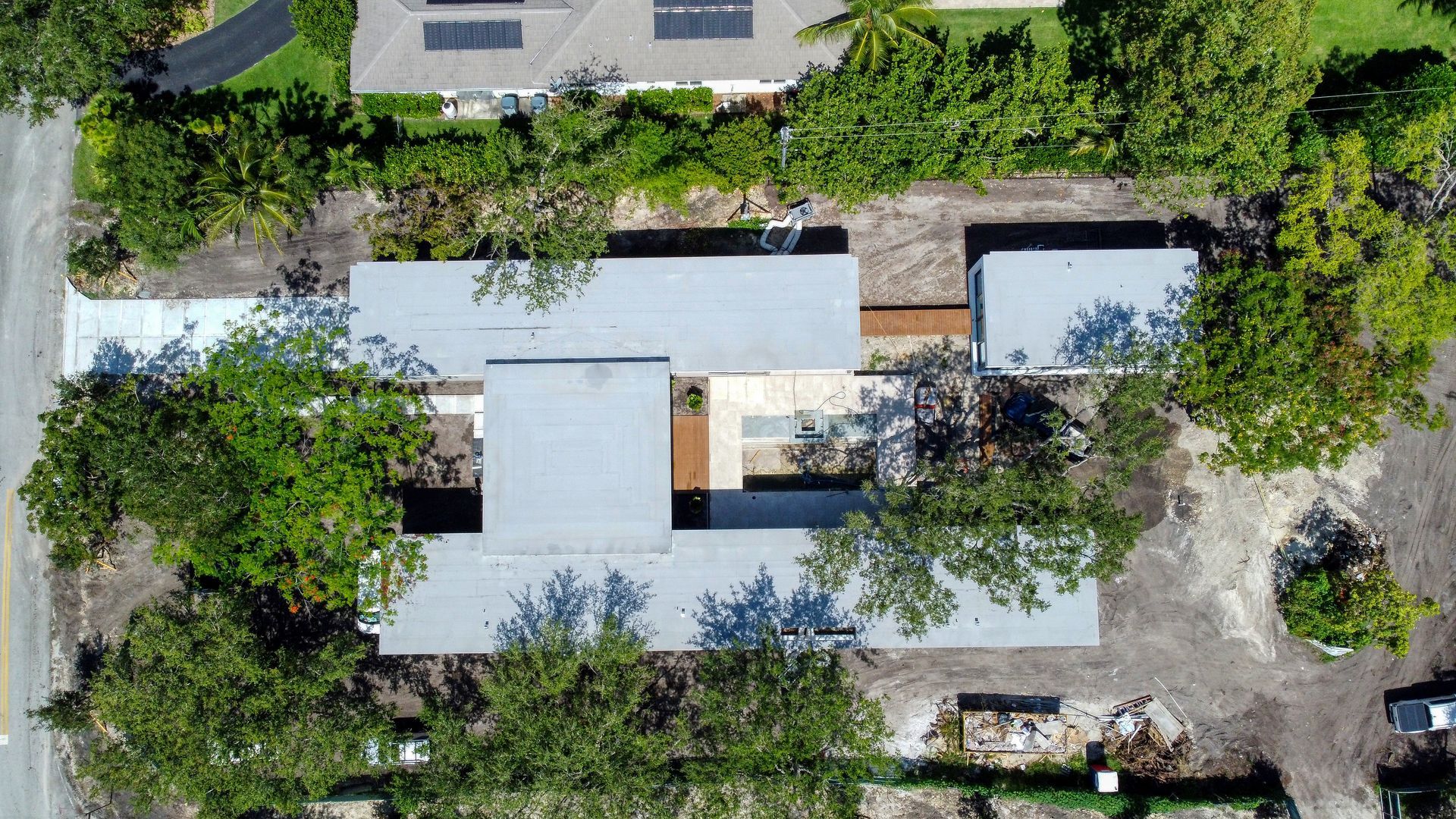 Overhead view of a modern building with multiple rectangular sections, surrounded by trees and landscaping.