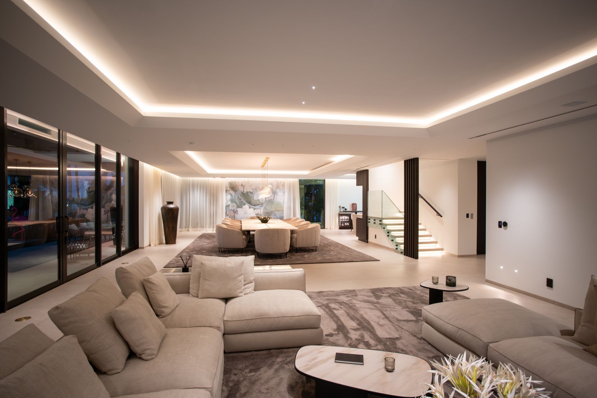 Spacious modern living room with neutral colors, sectional sofa, dining area, and large windows.