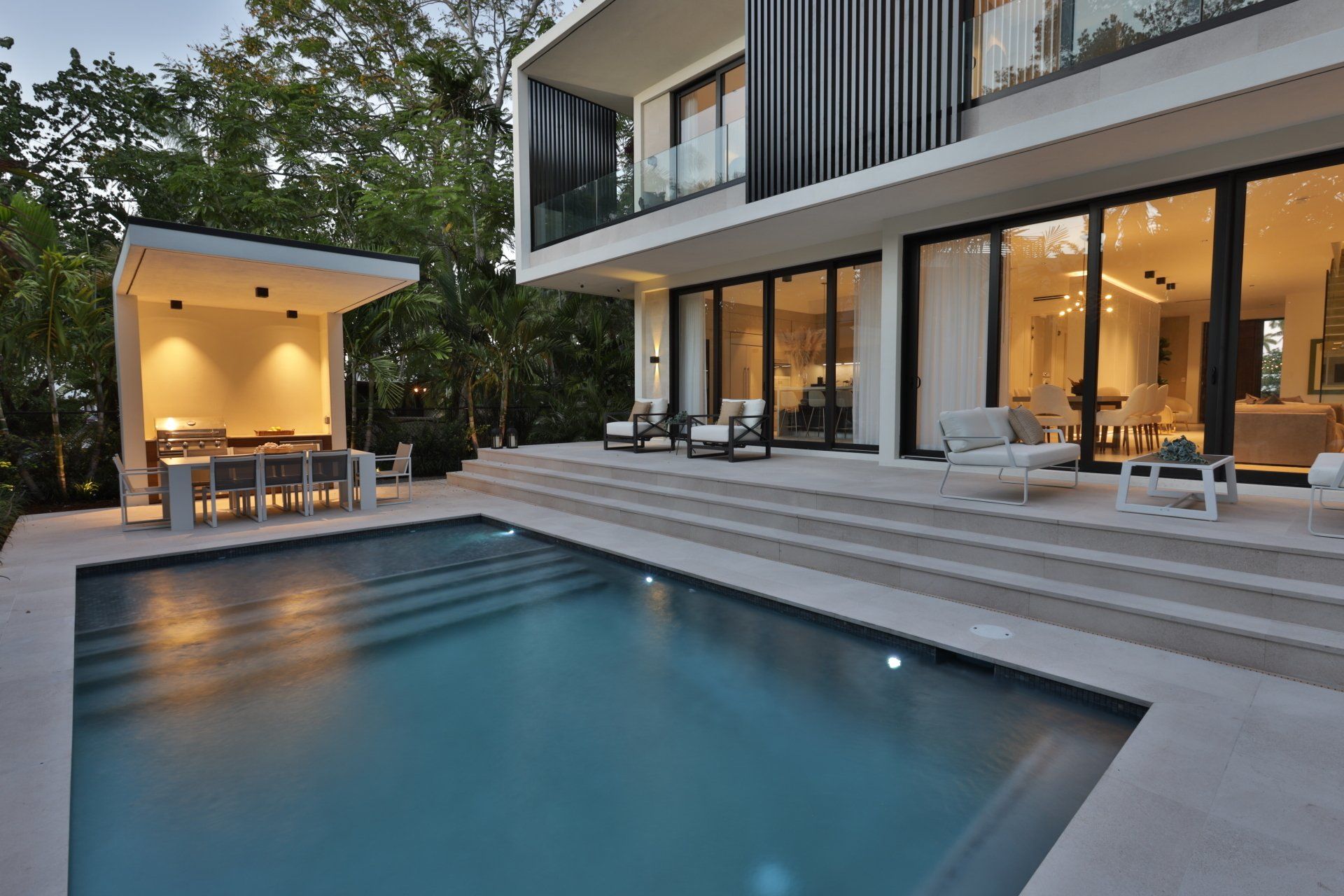 Modern home exterior with pool and outdoor dining area.