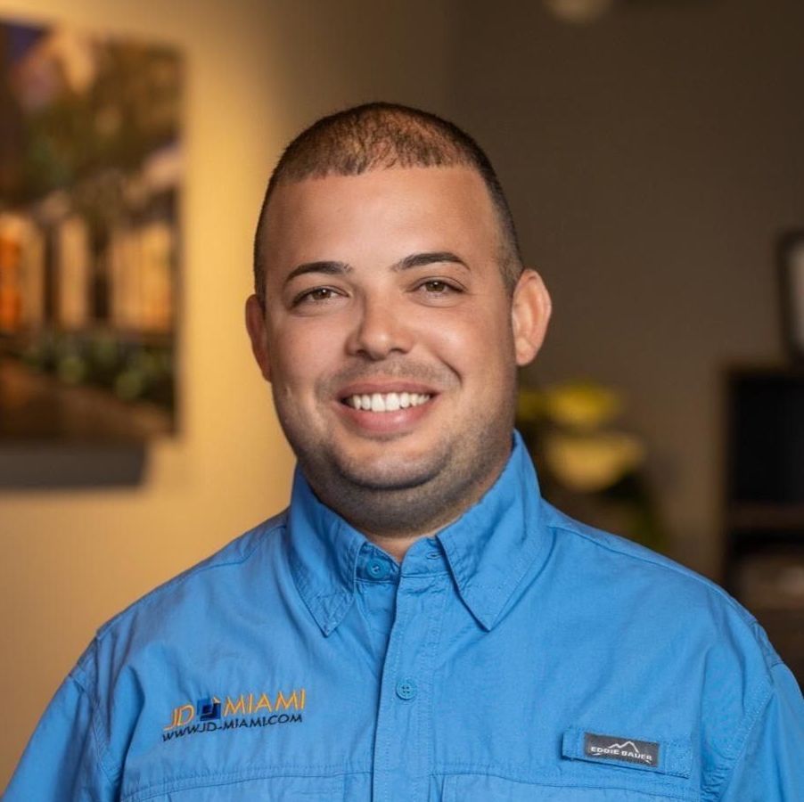 Man in blue shirt, smiling, in office setting.