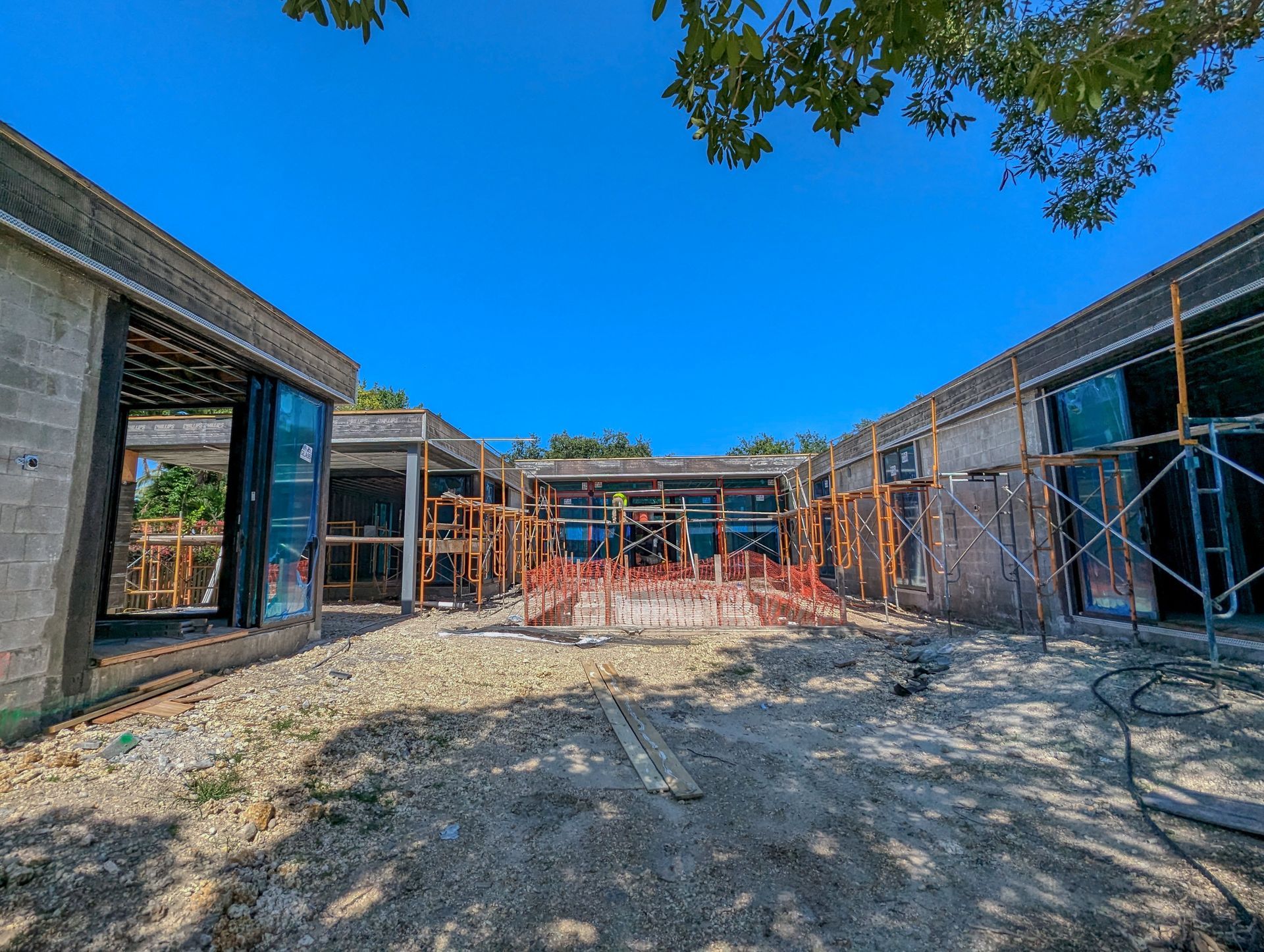 Construction site: concrete structures with scaffolding under a clear blue sky.