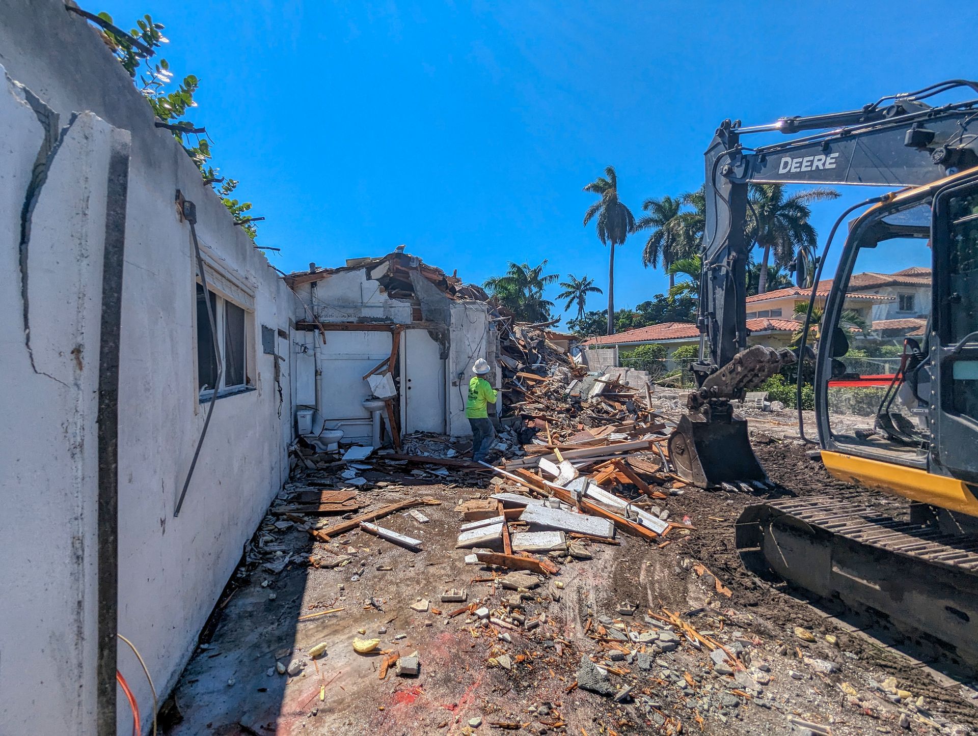 A large excavator is demolishing a building on a sunny day.