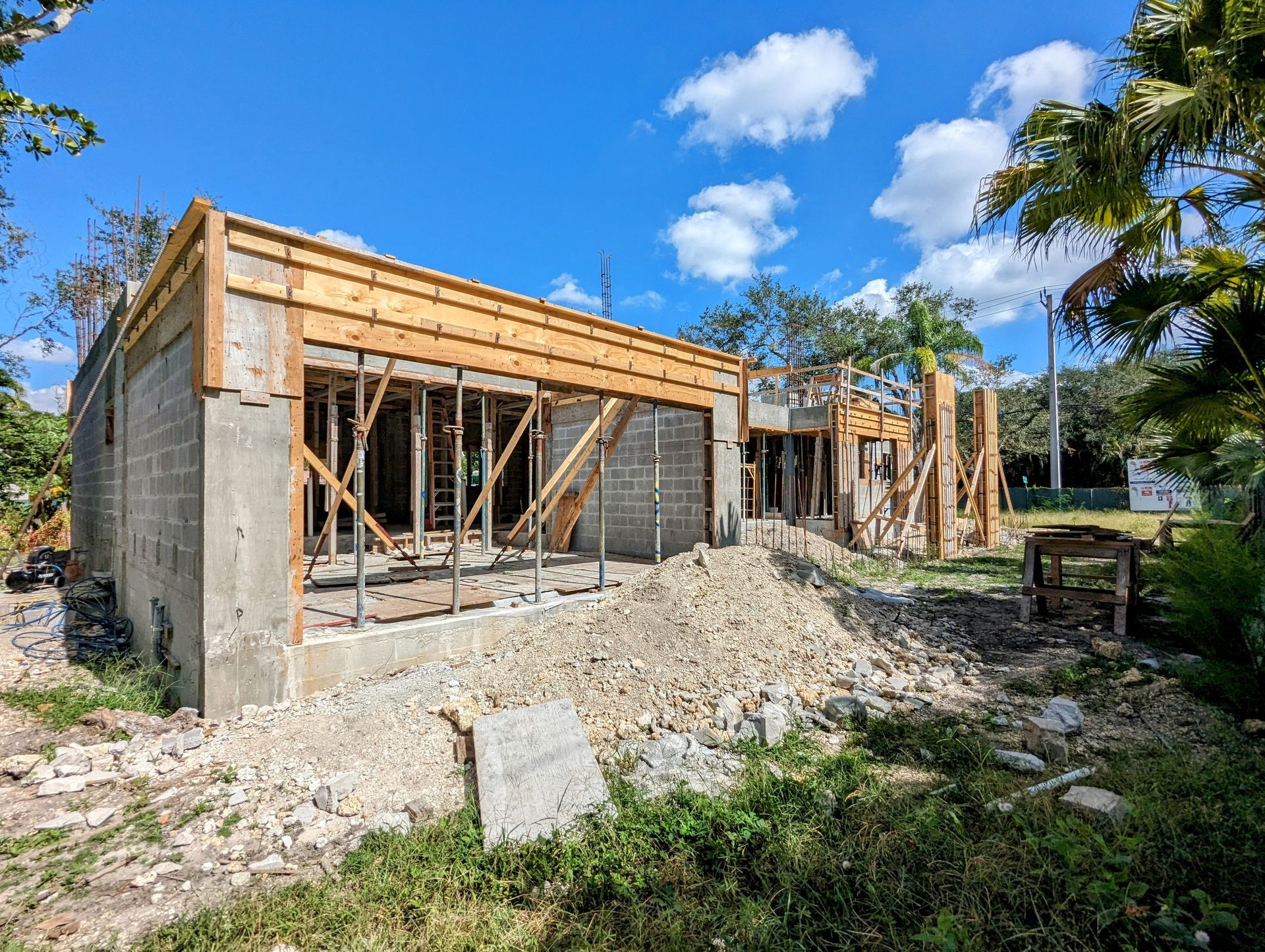 Building under construction with exposed wood framing and debris. Sunny outdoor setting.