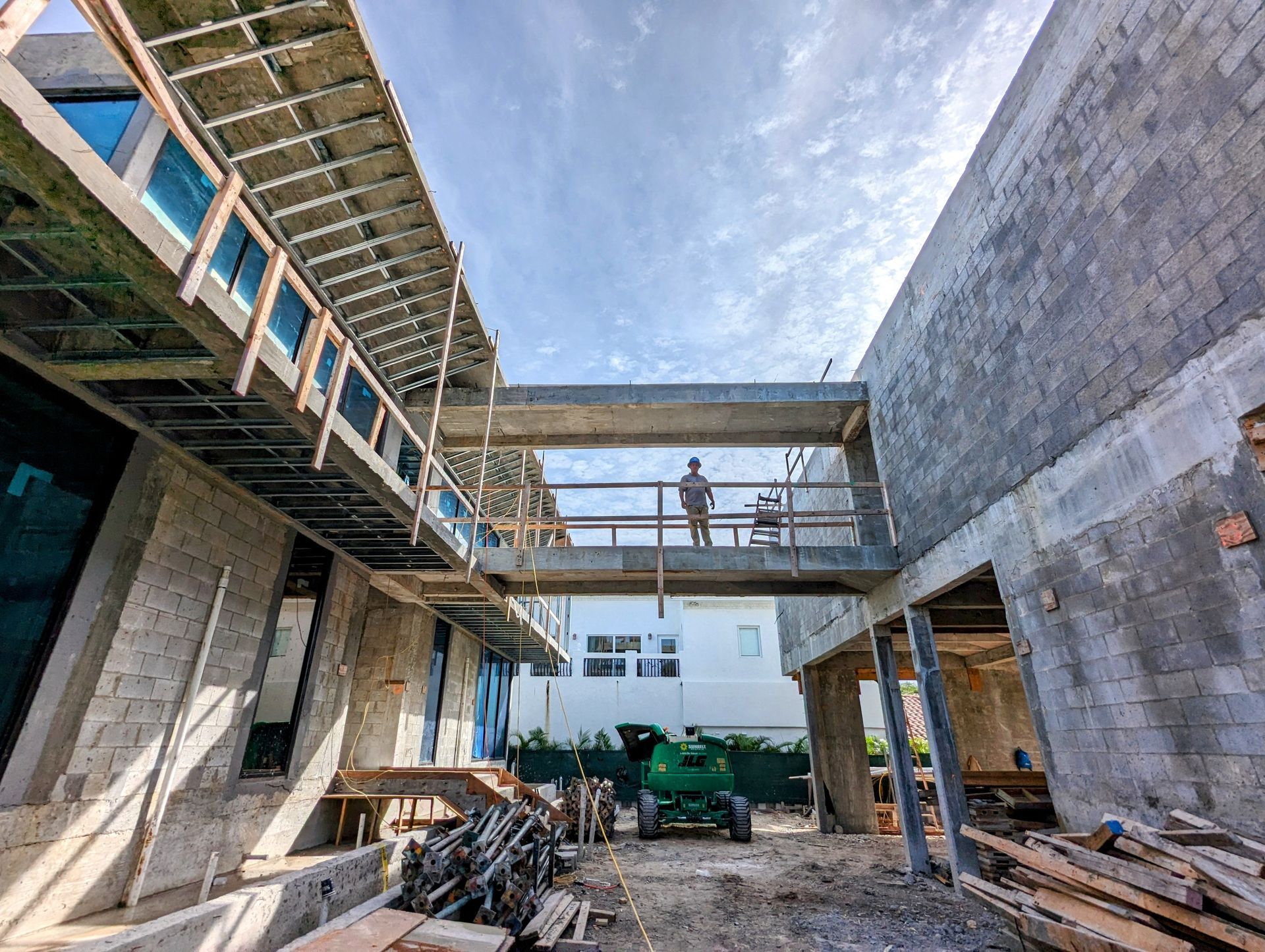 A man is standing on a bridge between two buildings under construction.