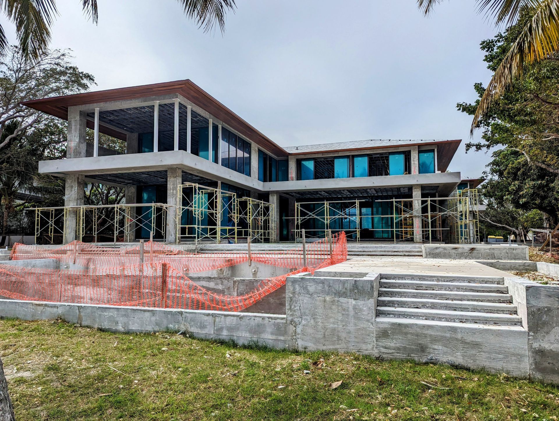 Construction of a modern two-story home with large glass windows and an unfinished facade.