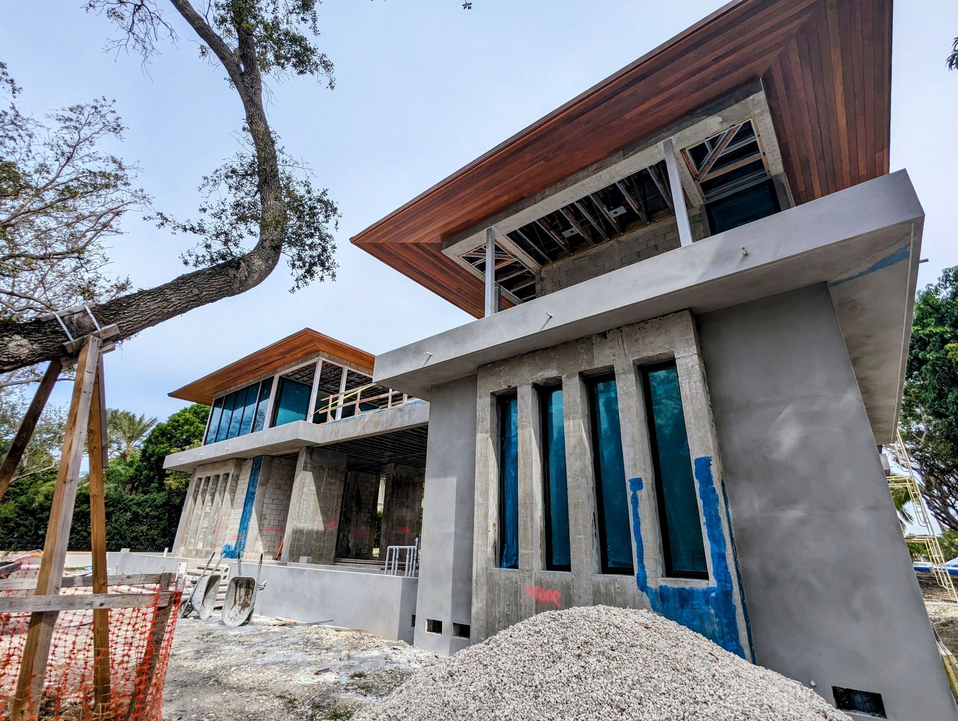 Two-story concrete buildings under construction with wood overhangs and blue window coverings.