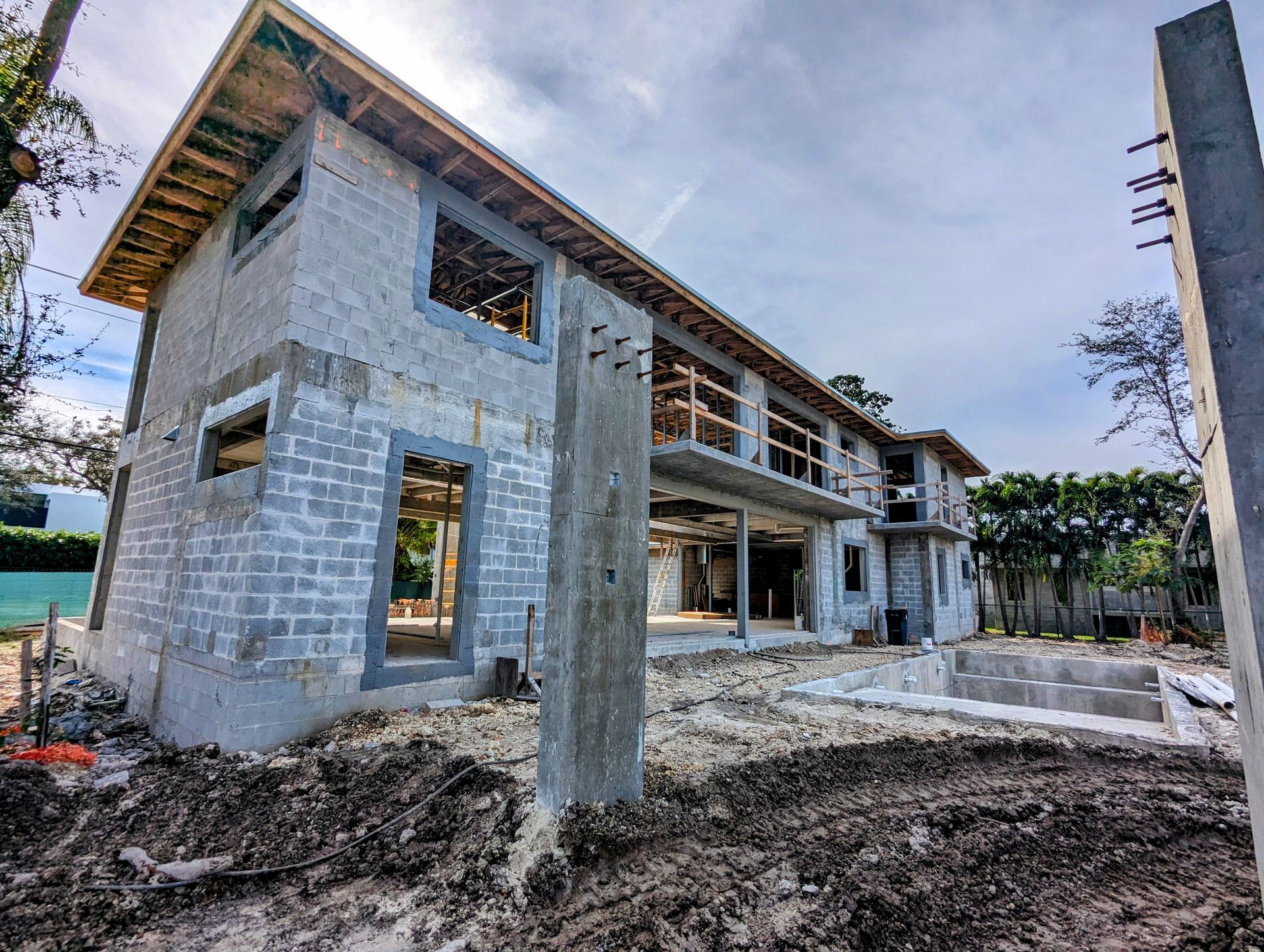 Construction site of a two-story building made of concrete blocks; windows and framing are visible.