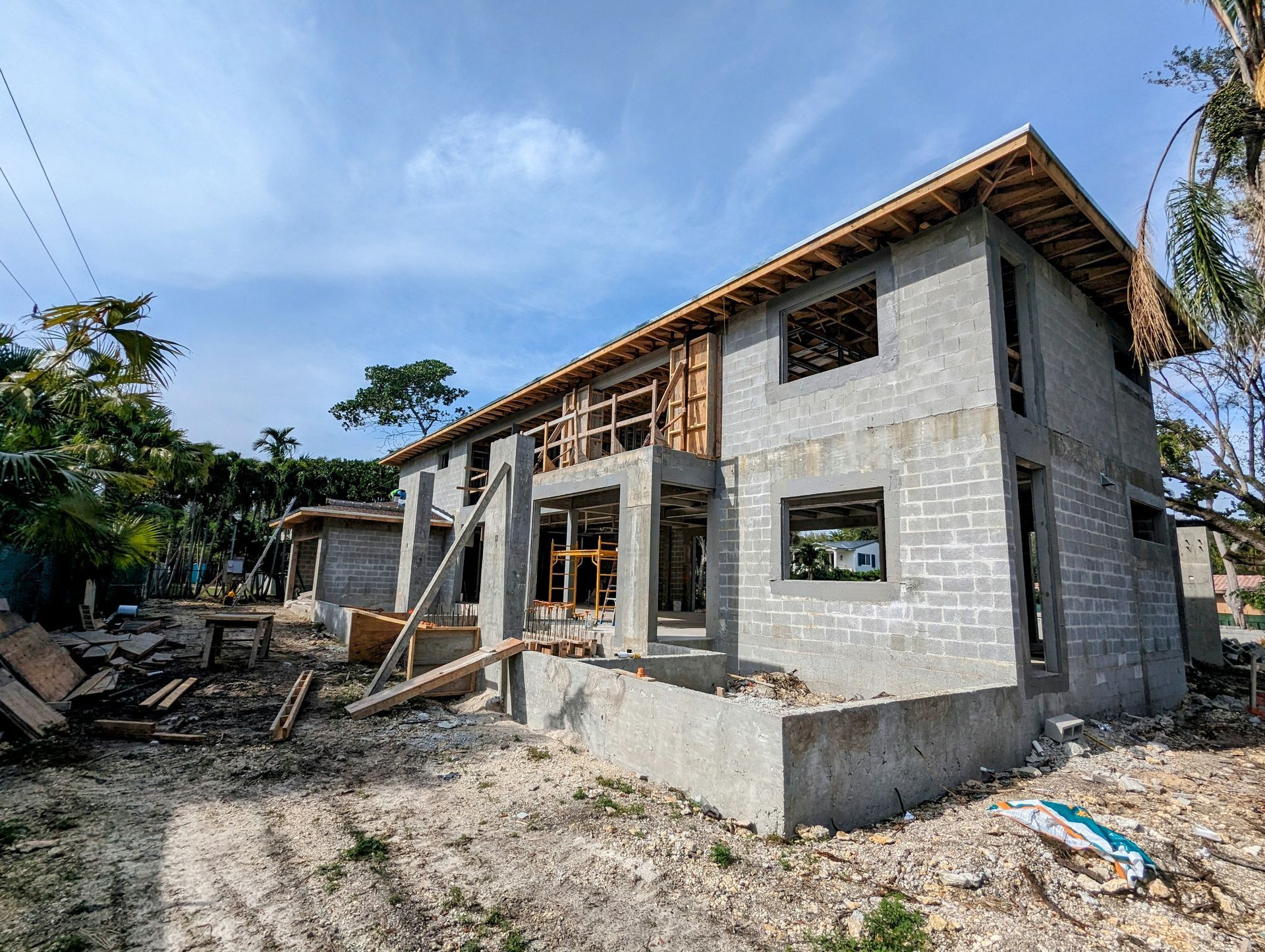 Building under construction with concrete block walls and wooden framing, set in a yard.