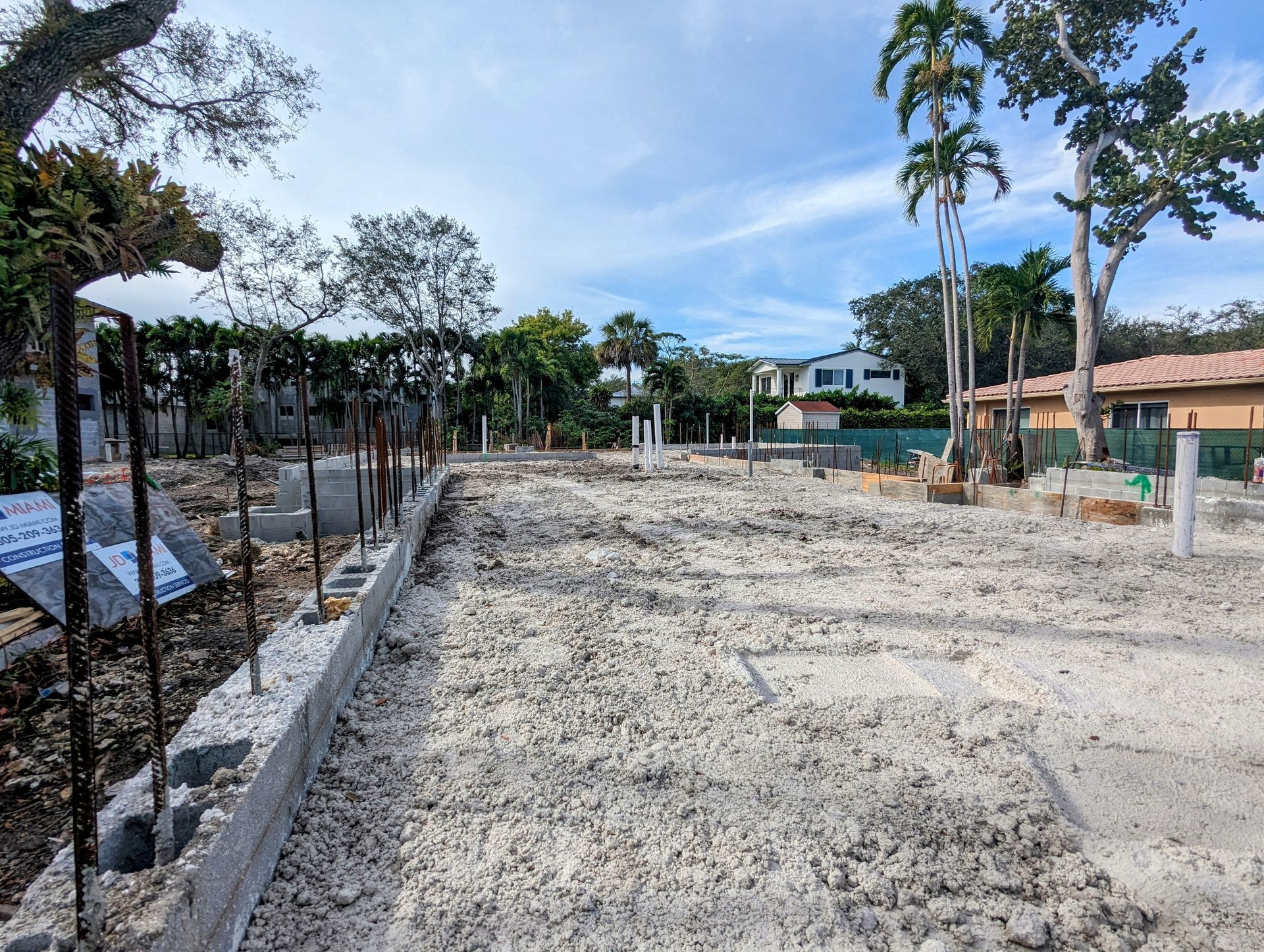 Construction site with concrete foundation and exposed rebar, preparing for a building.