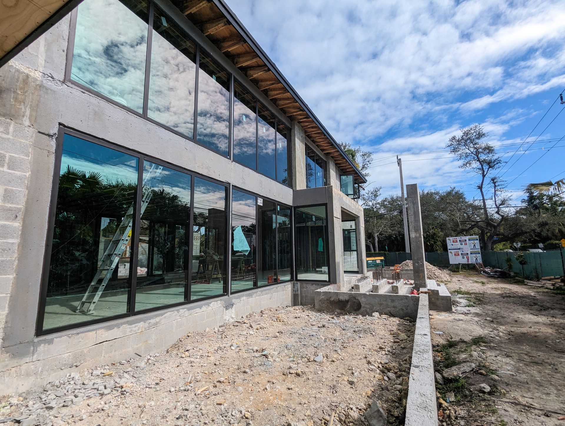 Building under construction with large windows and a gravel lot.