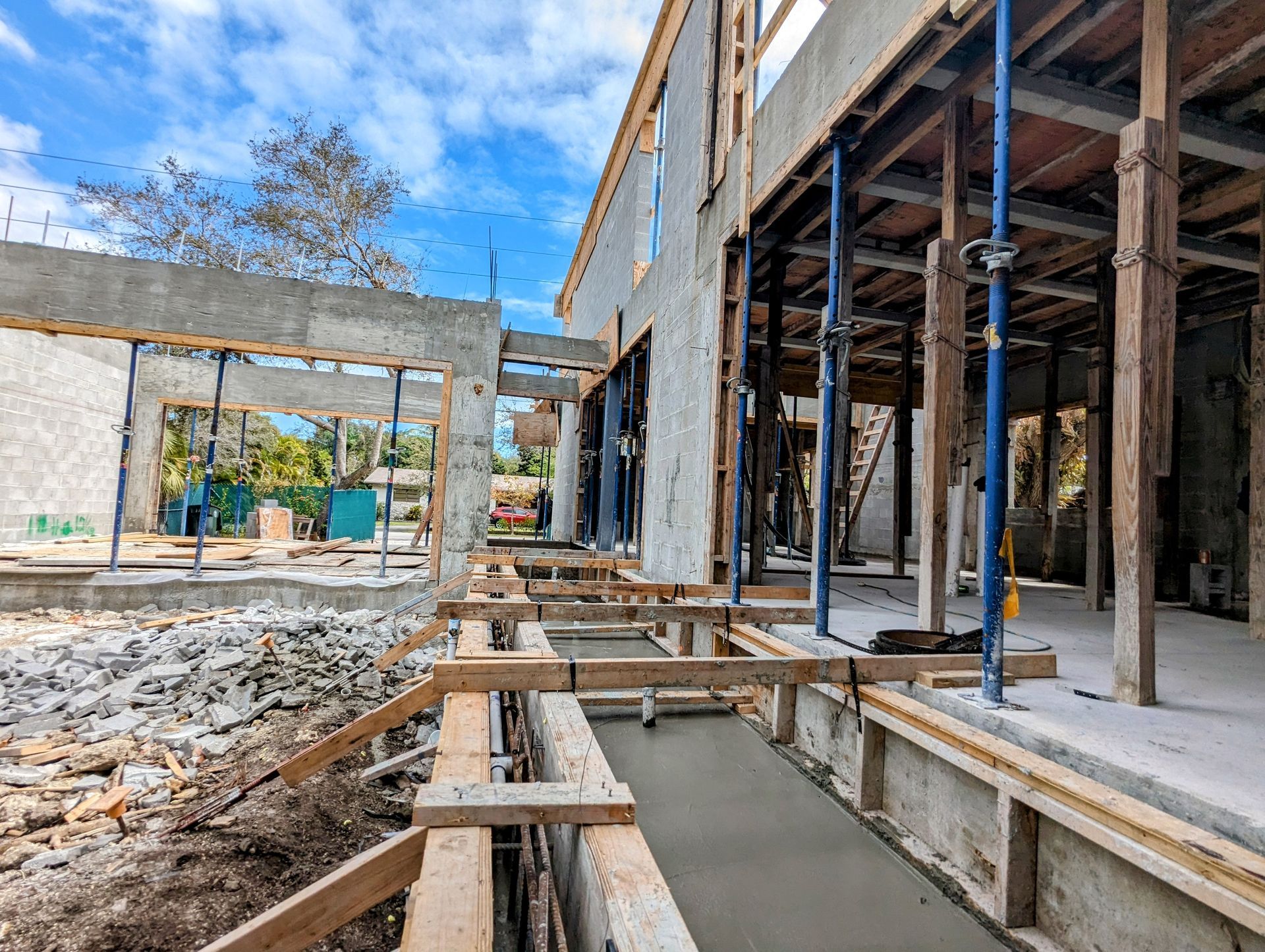 Construction site; building frame with concrete and wooden supports against a blue sky.