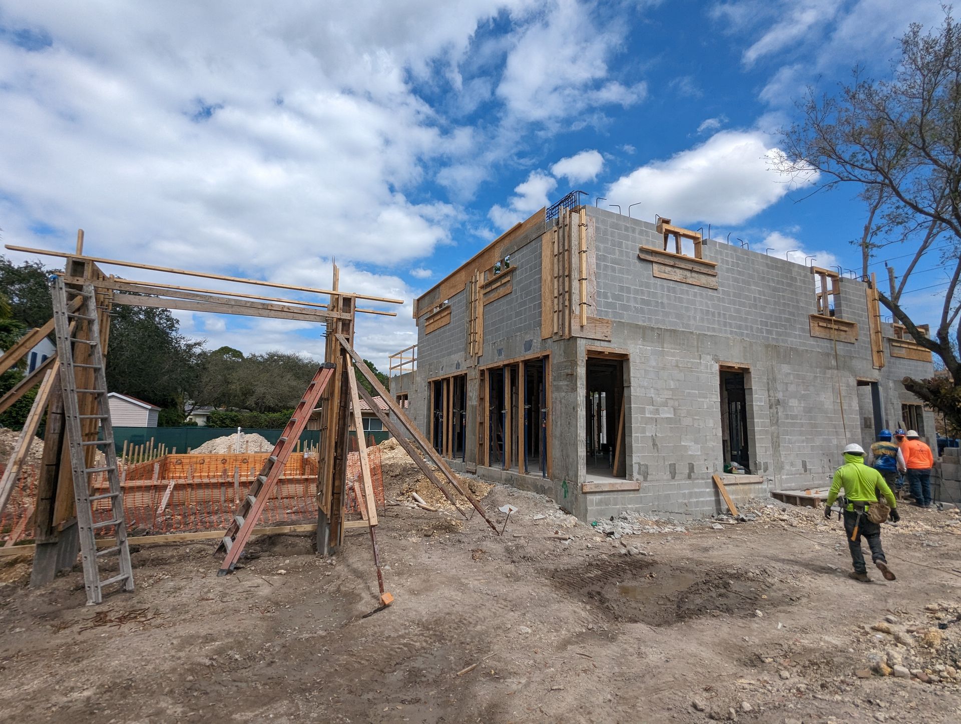 Construction site with concrete block building and scaffolding under a cloudy sky.