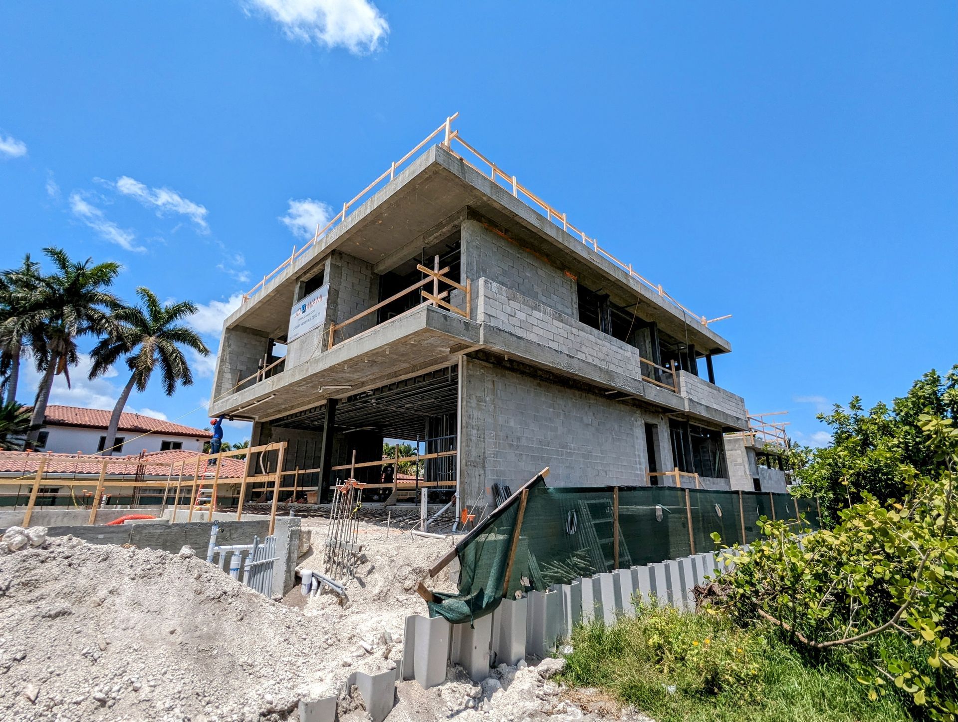 A large house is being built on top of a dirt hill.