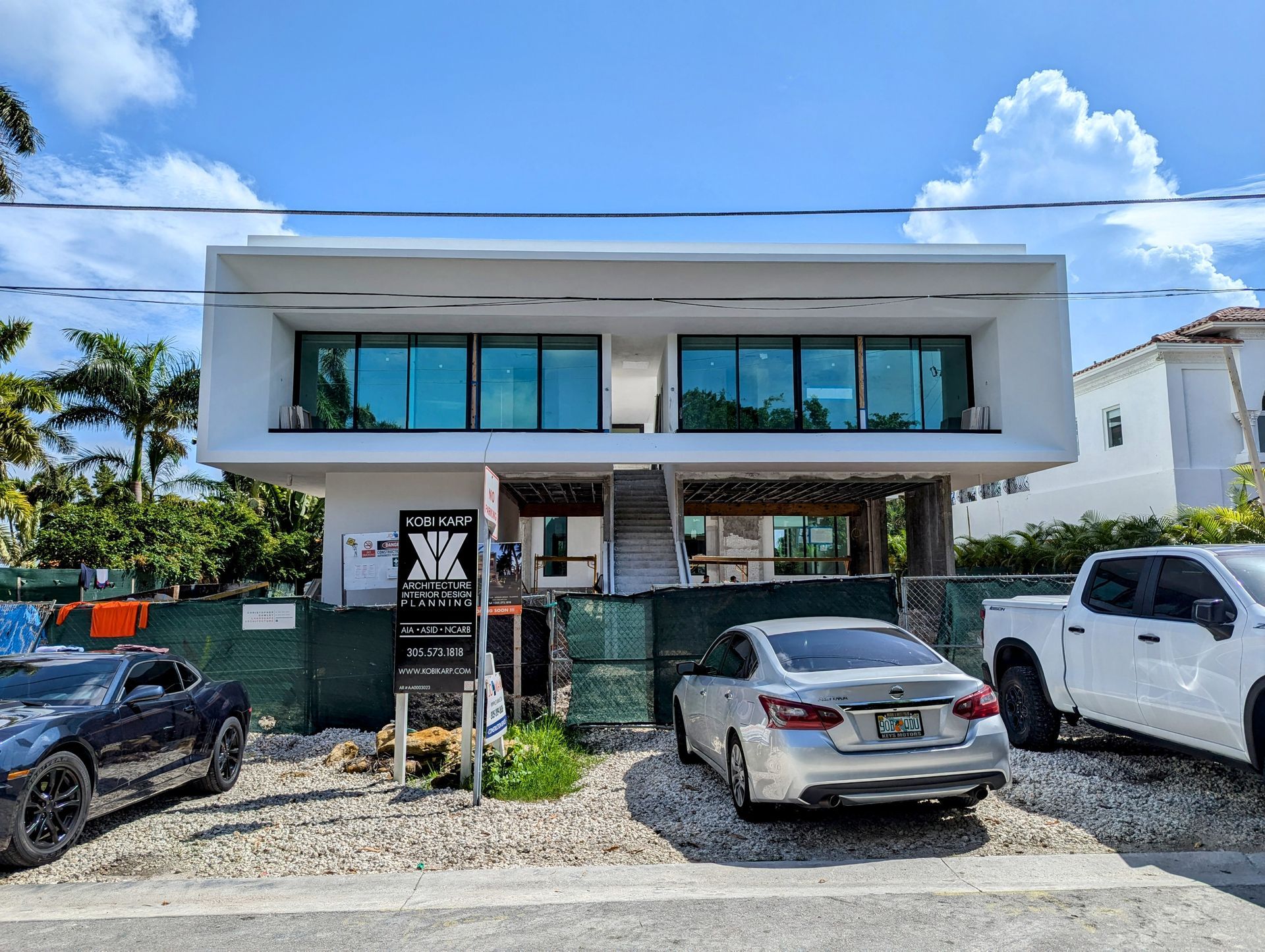 Two cars are parked in front of a large building.