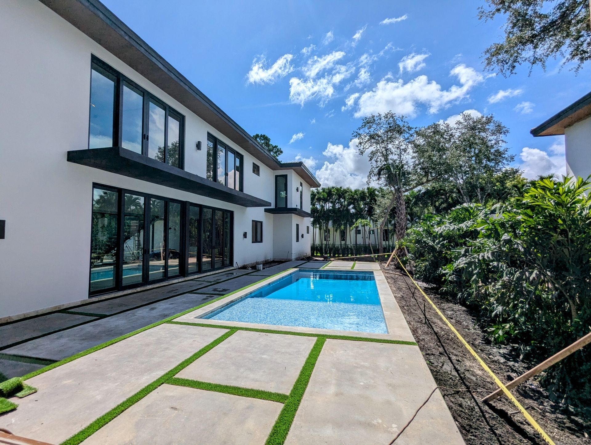Modern two-story house with pool, large windows, and manicured yard on a sunny day.